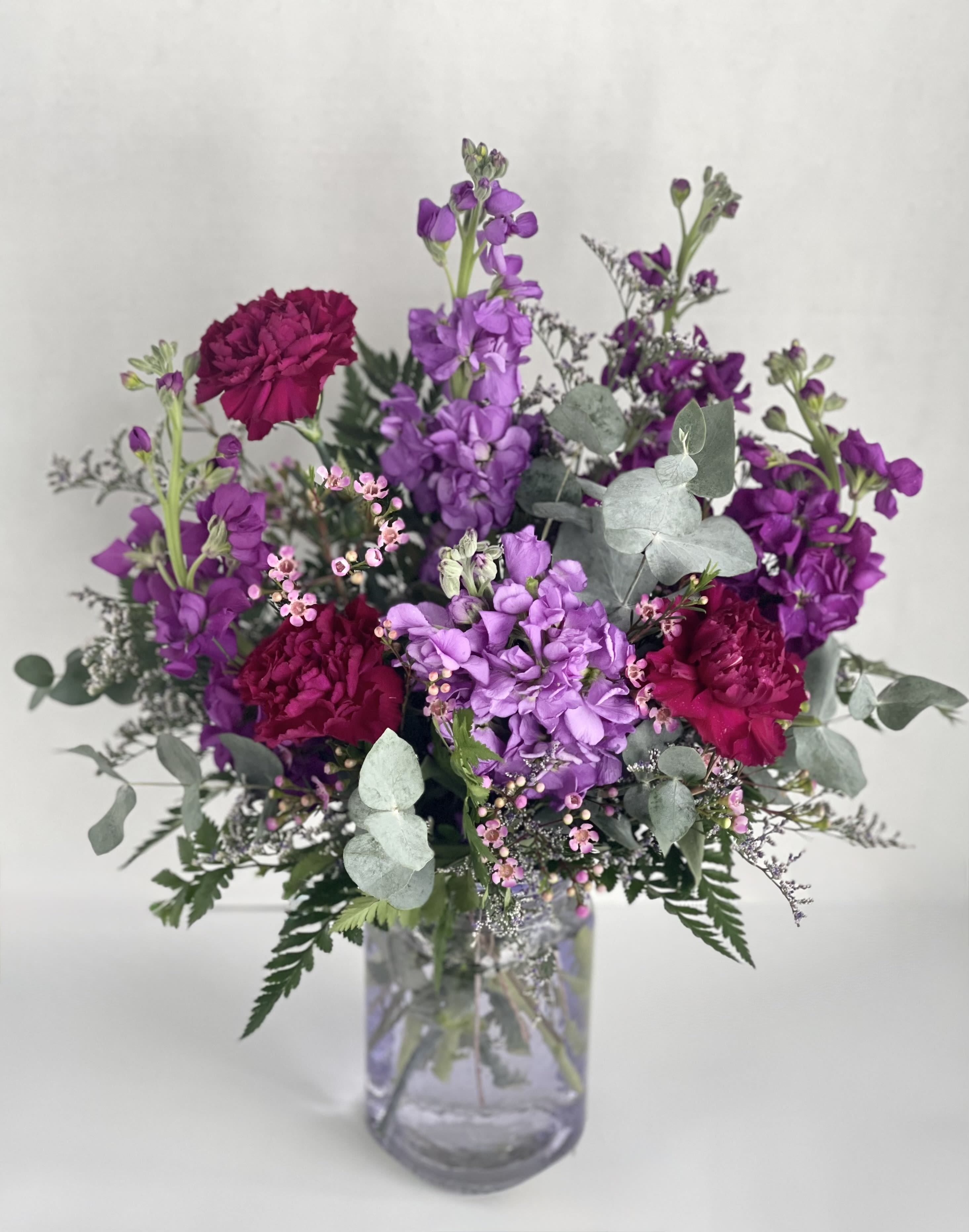 Purple and magenta flowers arranged in a clear glass vase