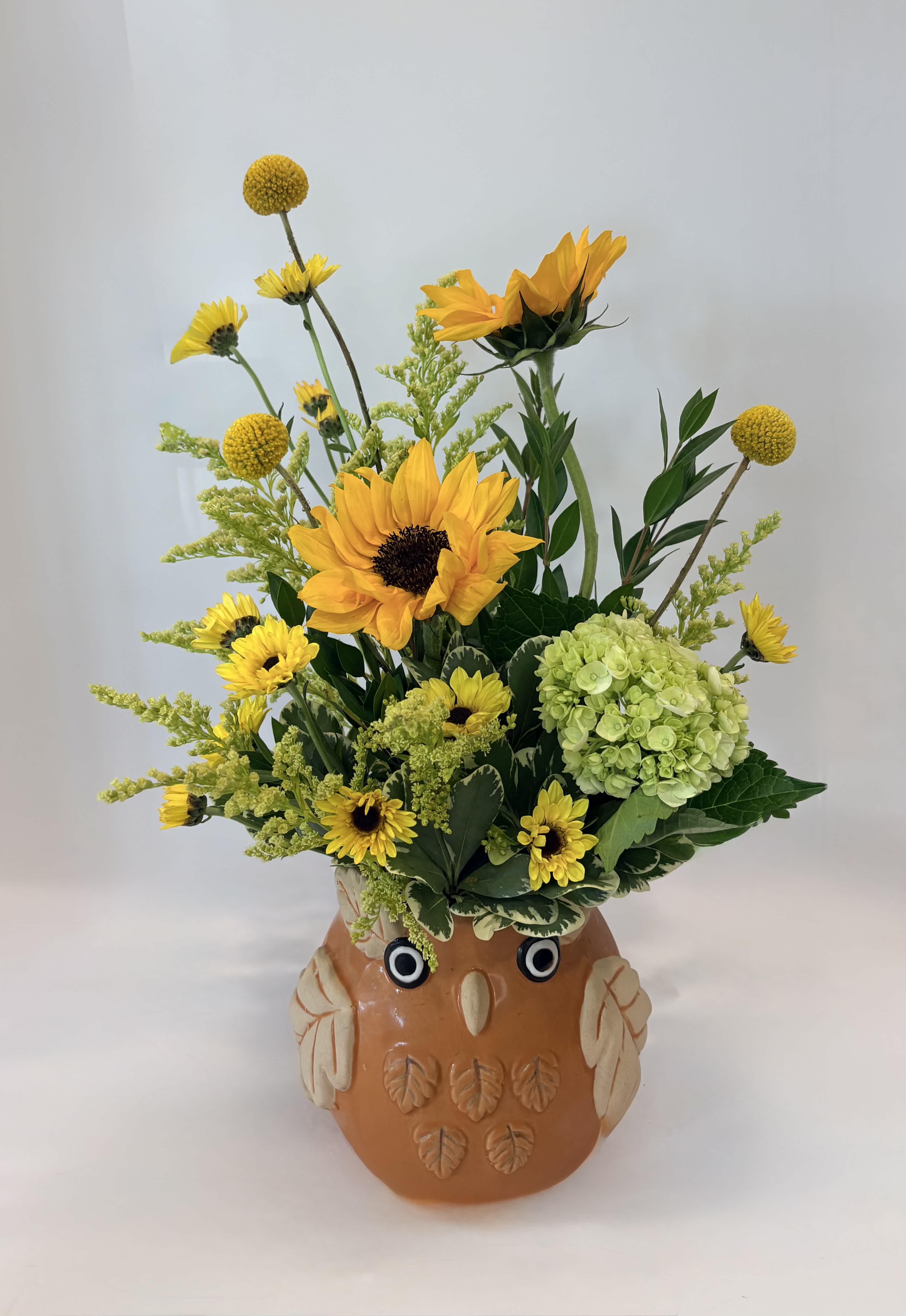 Sunflower and yellow flower arrangement in an owl-shaped ceramic pot
