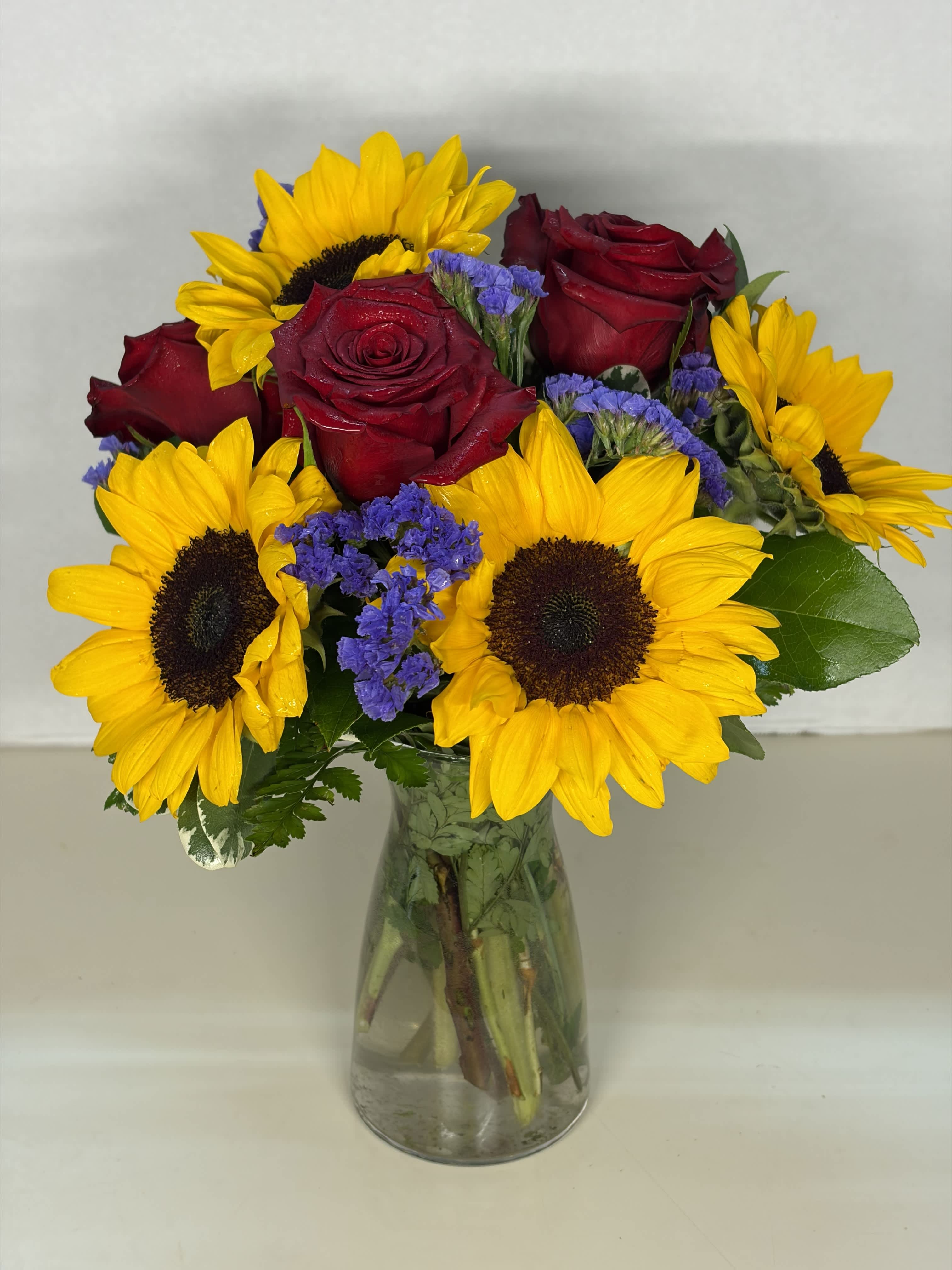 Bouquet of red roses and yellow sunflowers in a glass vase
