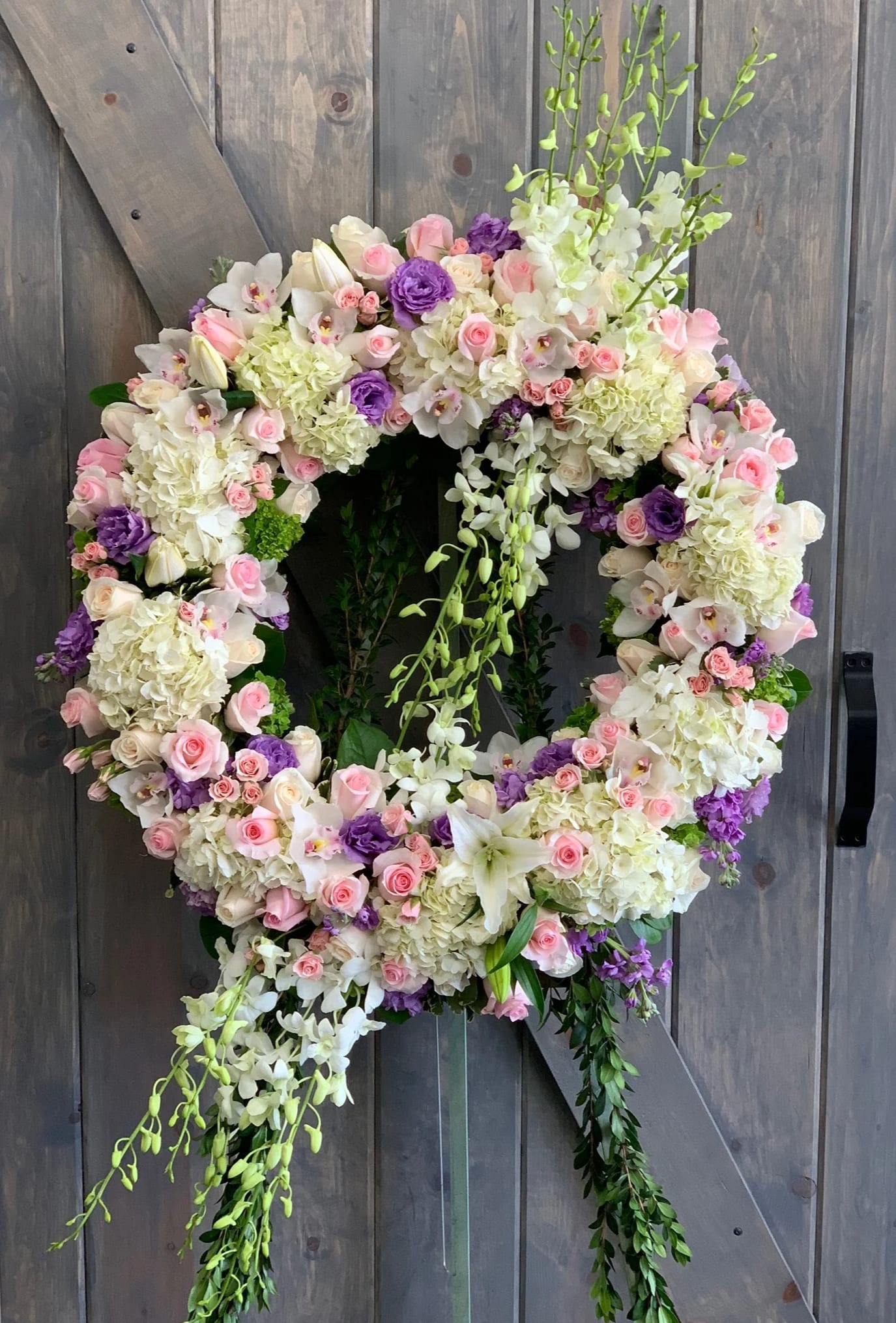 Large floral wreath with pink, white, and purple blooms on a wooden backdrop