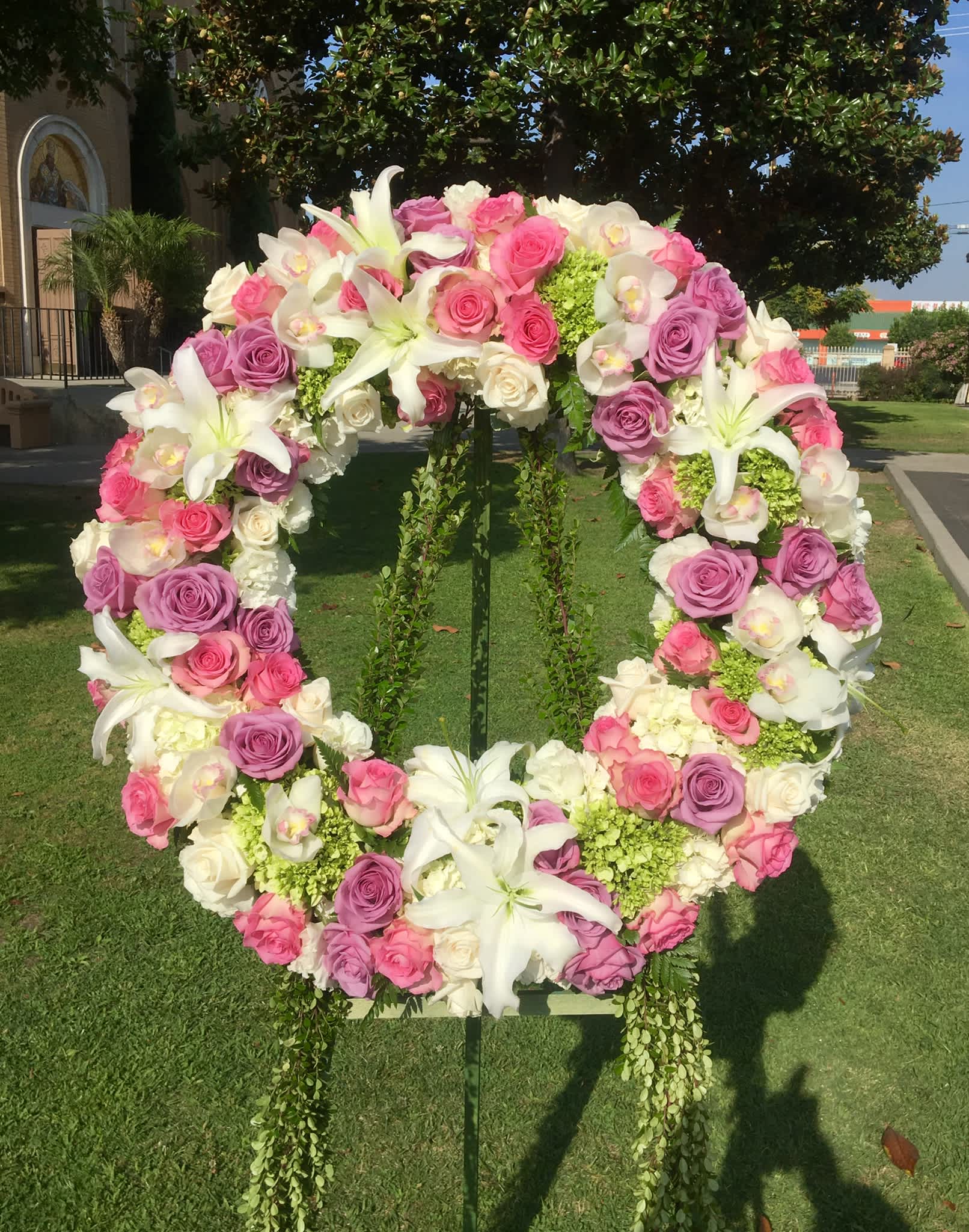 Large floral wreath of pink and white roses with white lilies