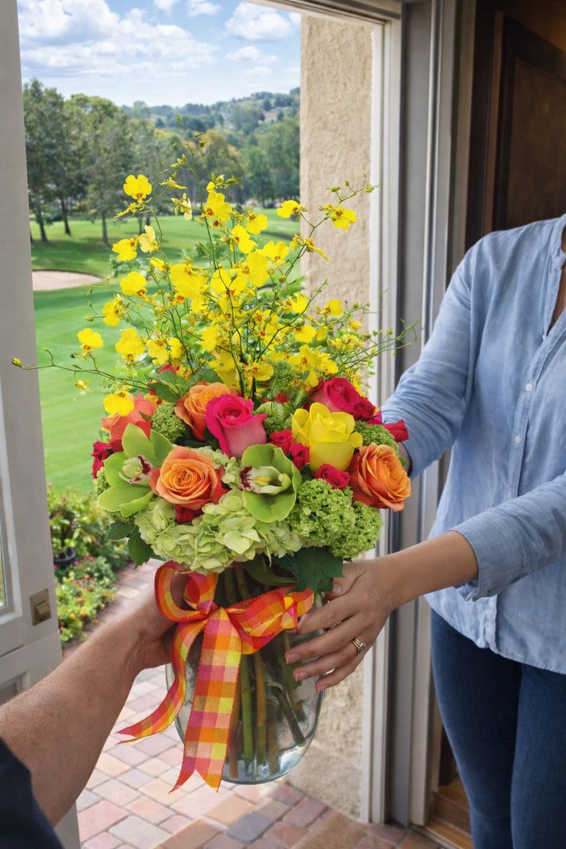 Colorful bouquet of roses and yellow orchids in a glass vase with ribbon
