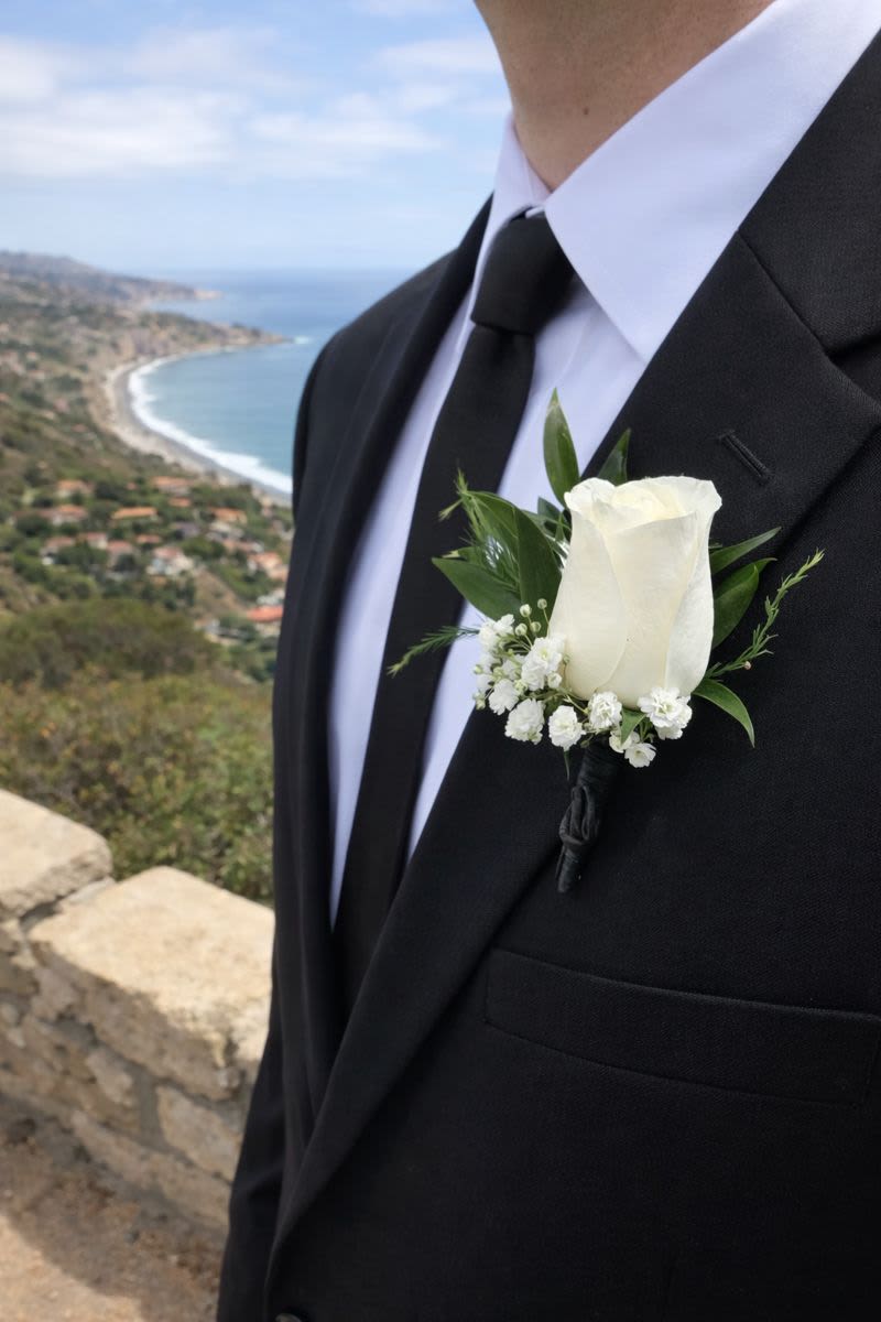 White rose boutonniere on a black suit jacket