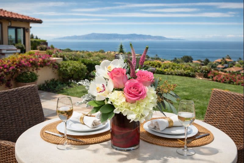 Pink and white floral centerpiece in a glass vase on an outdoor table