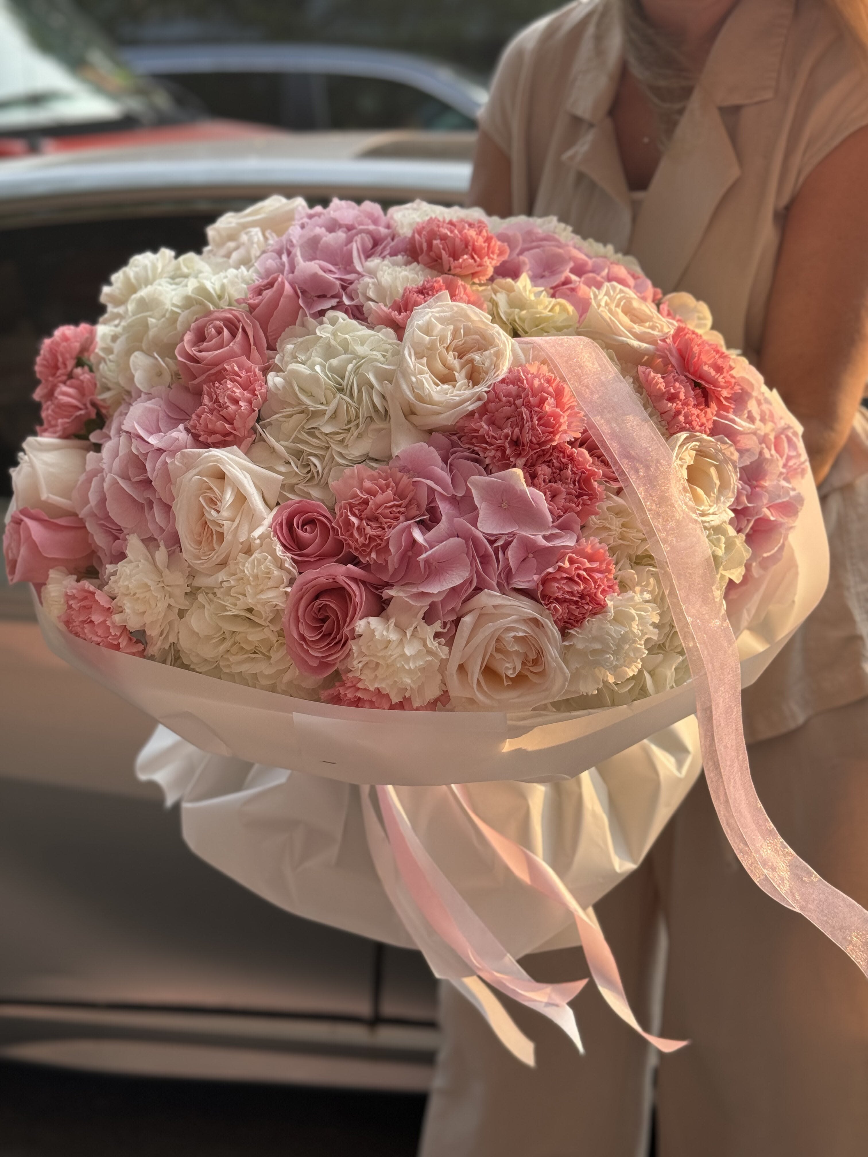 Large bouquet of pink and white roses and carnations wrapped with ribbon
