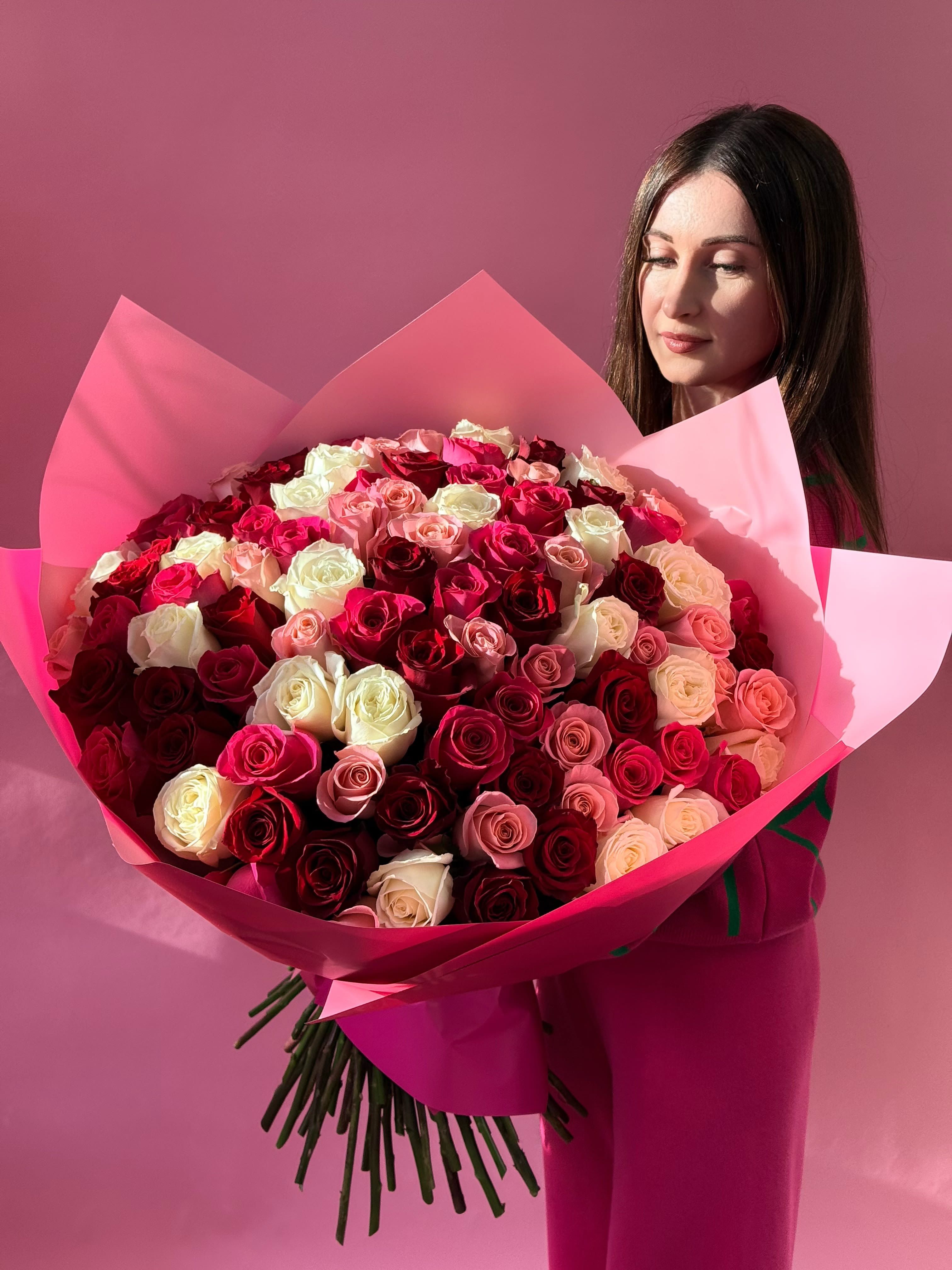 Large bouquet of pink, red, and white roses wrapped in pink paper