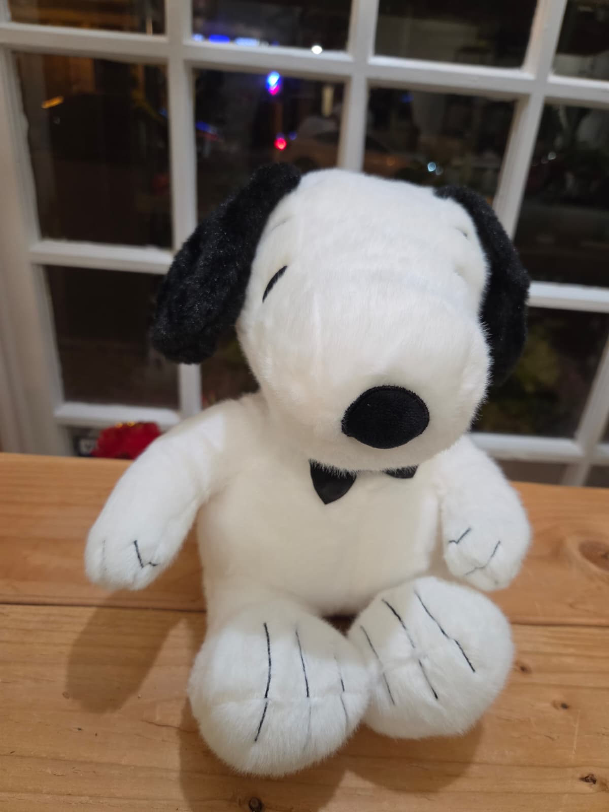 Plush Snoopy stuffed animal sitting on a wooden surface