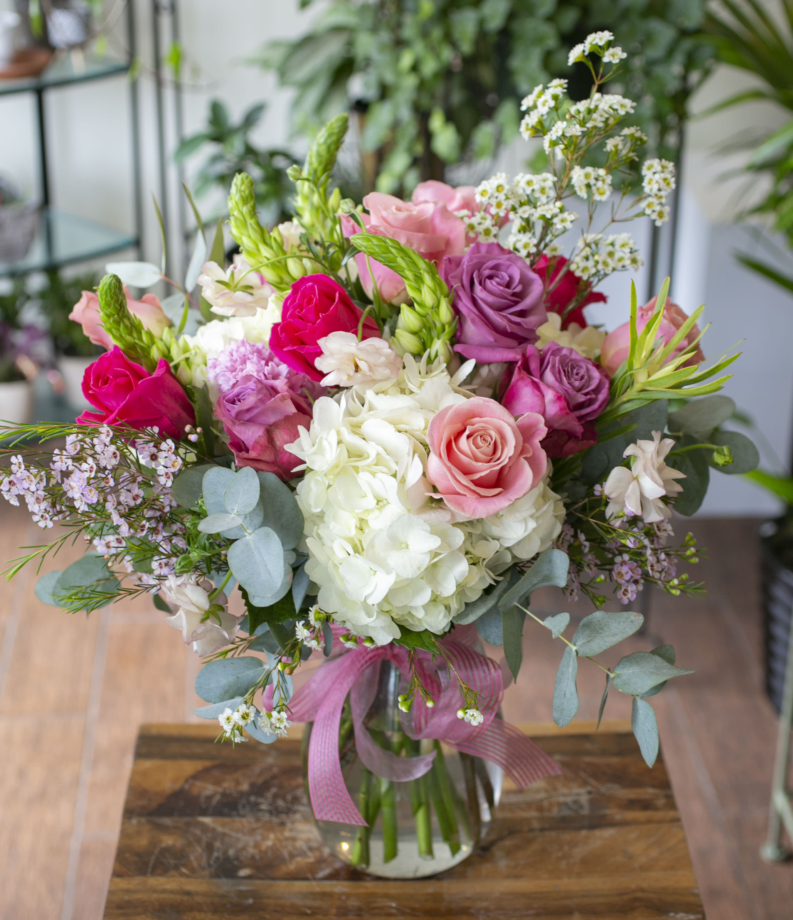 Pink and white rose bouquet in a glass vase with a ribbon