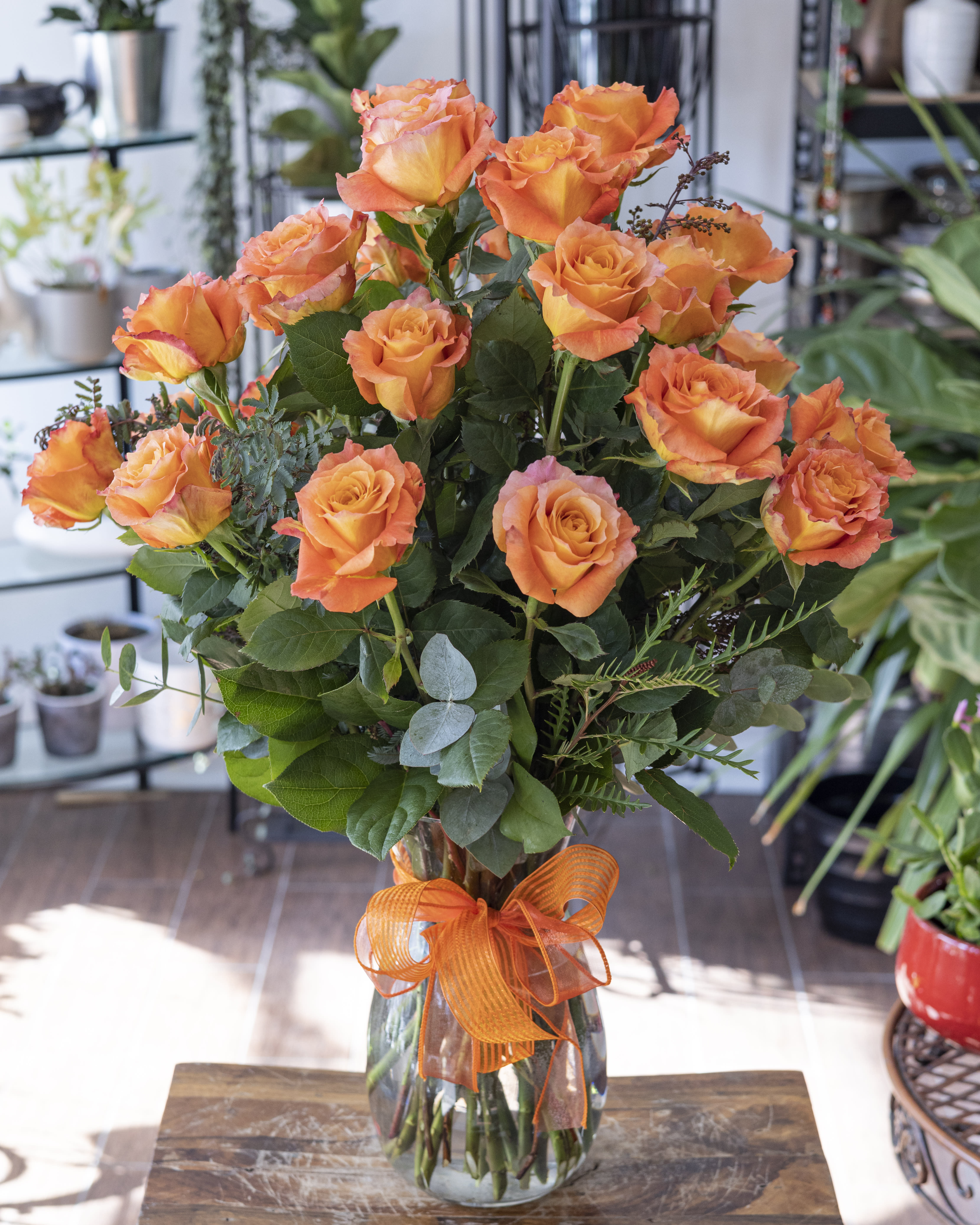 Orange roses in a clear glass vase with an orange ribbon