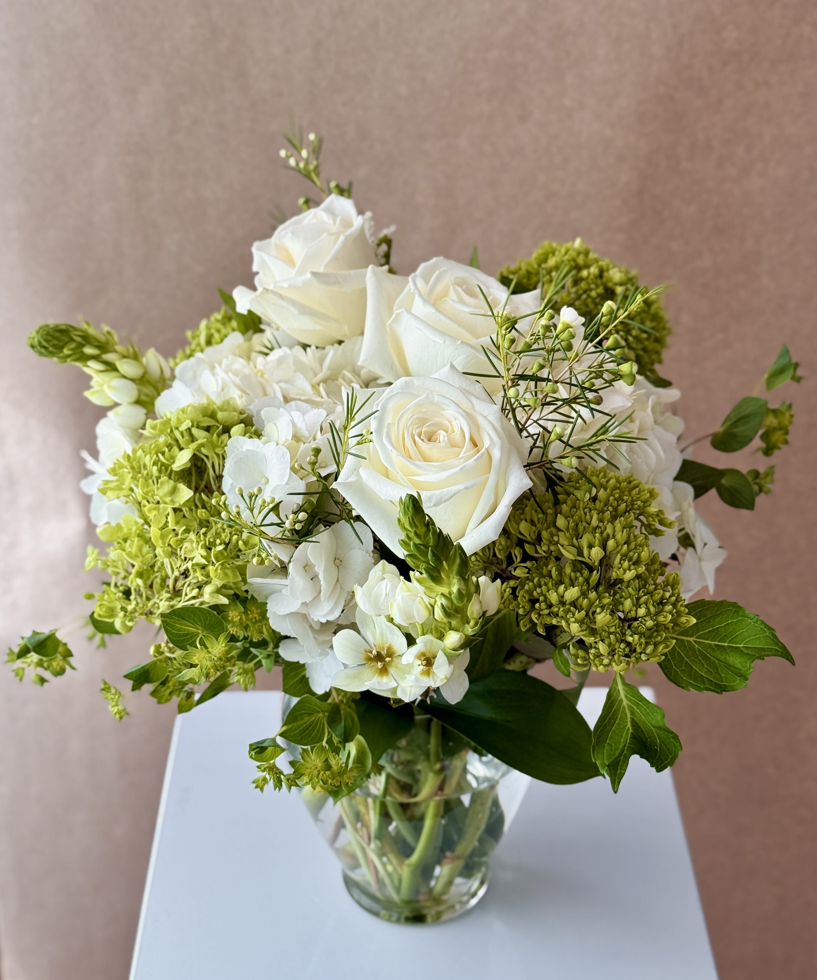 White roses and green hydrangeas in a clear glass vase
