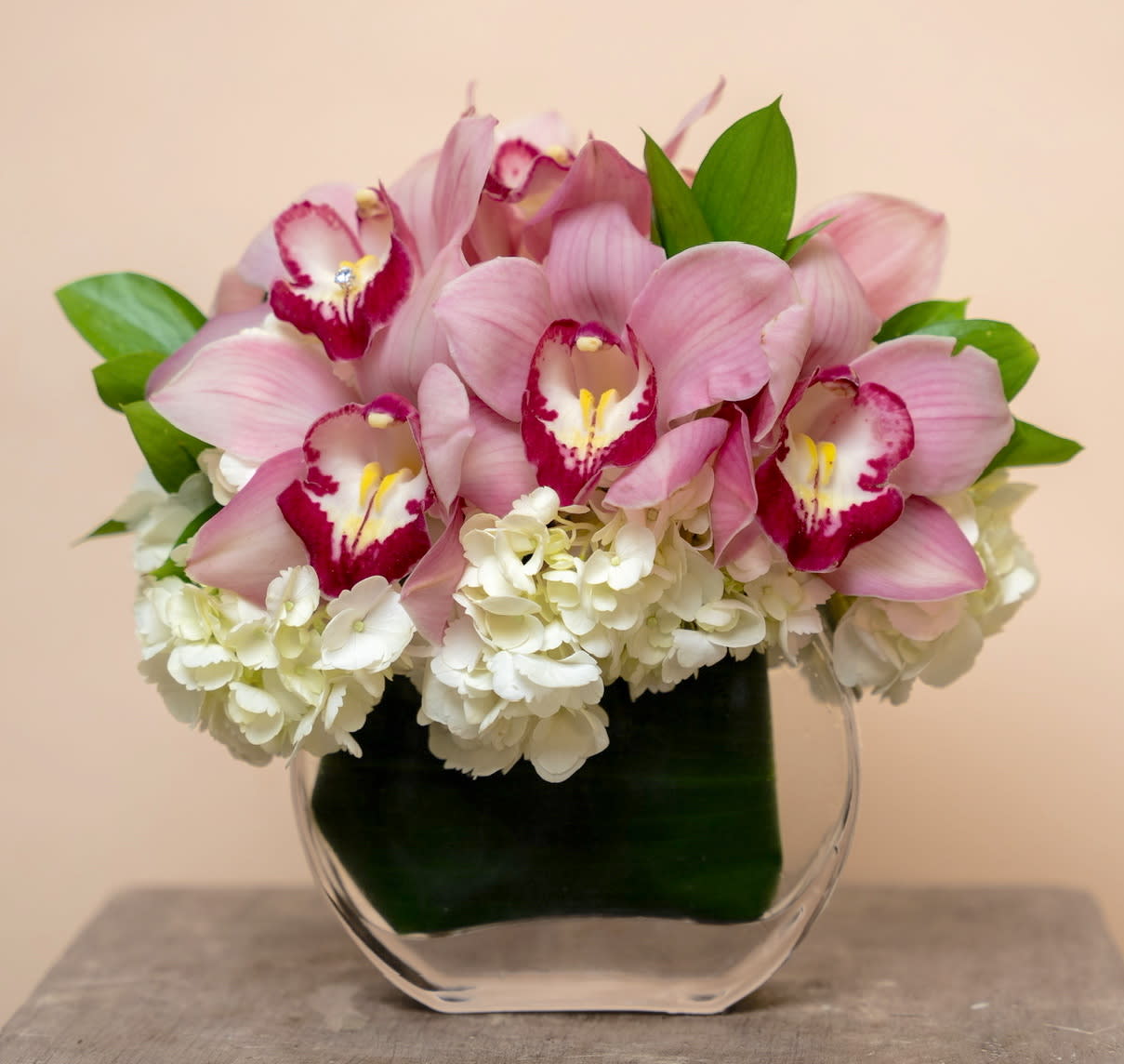 Pink orchids and white hydrangeas in a clear glass vase