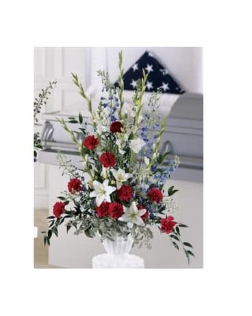 Standing floral spray with red, white, and blue flowers in a white urn