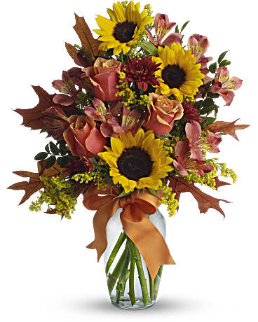 Bouquet of sunflowers, roses, and alstroemeria in a glass vase with orange ribbon