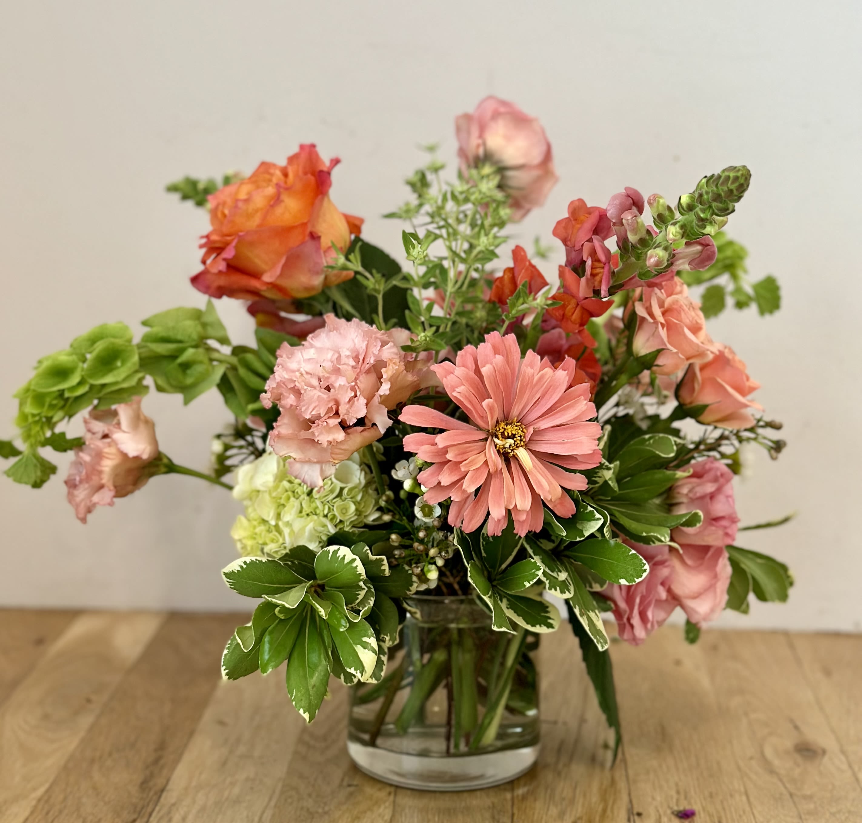 Mixed pink and orange flowers arranged in a clear glass vase