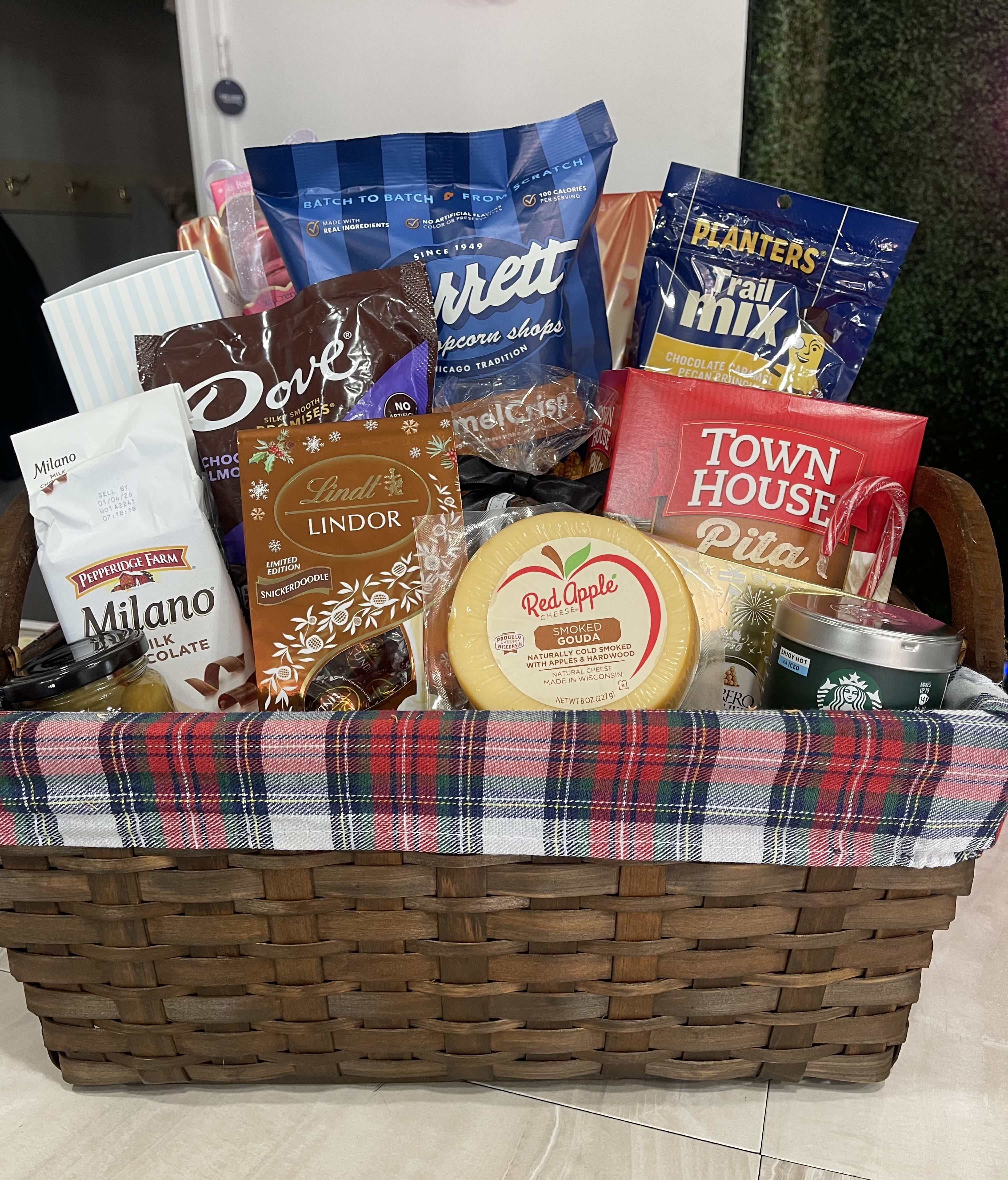 Basket of assorted snacks and sweets with a plaid liner