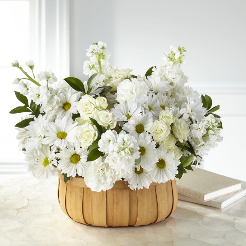 White daisies and roses arranged in a woven basket