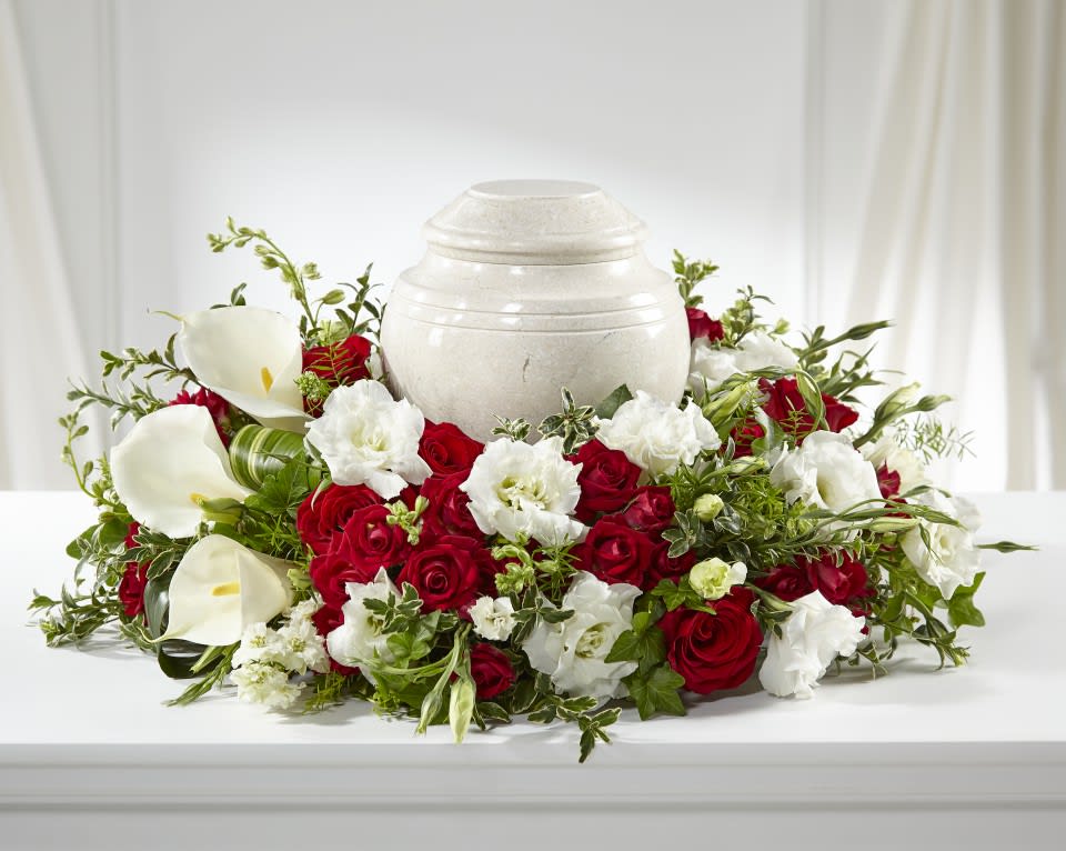 Red roses and white calla lilies arranged around a white urn