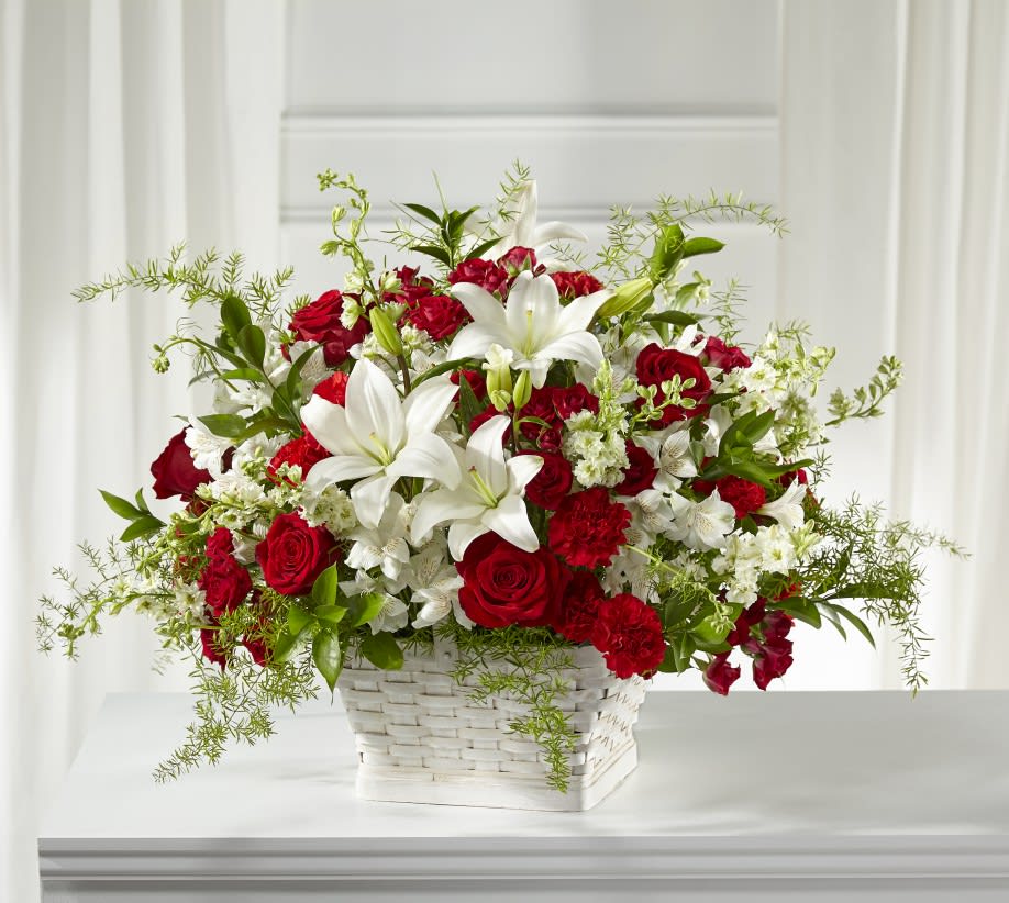 Red roses and white lilies arranged in a white basket