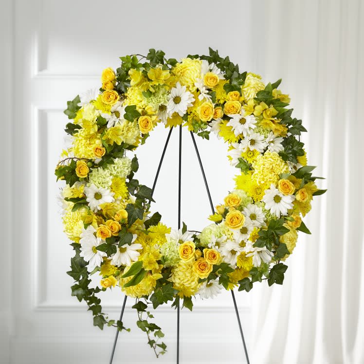 Golden Remembrance Wreath - Whether yellow was their favorite color or it captures the essence of their radiance, a ring of bright blooms thoughtfully displays your sentiment. Our Golden Remembrance Wreath is composed of spray roses, daisy pompons, carnations and more. Each flower is selected to beautifully accent one another and the love you are sending. 