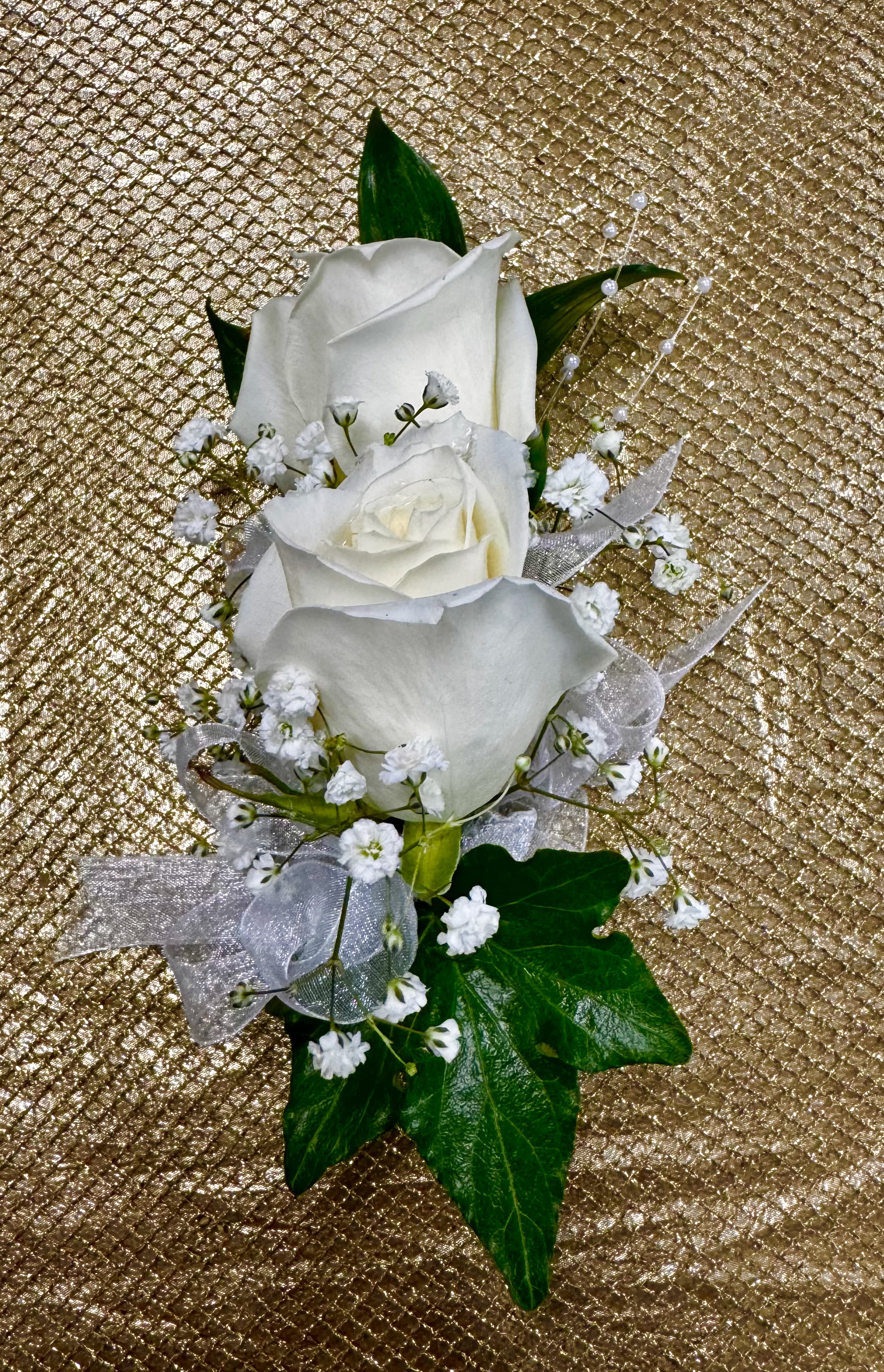 White rose boutonniere with baby's breath and ribbon on a gold background