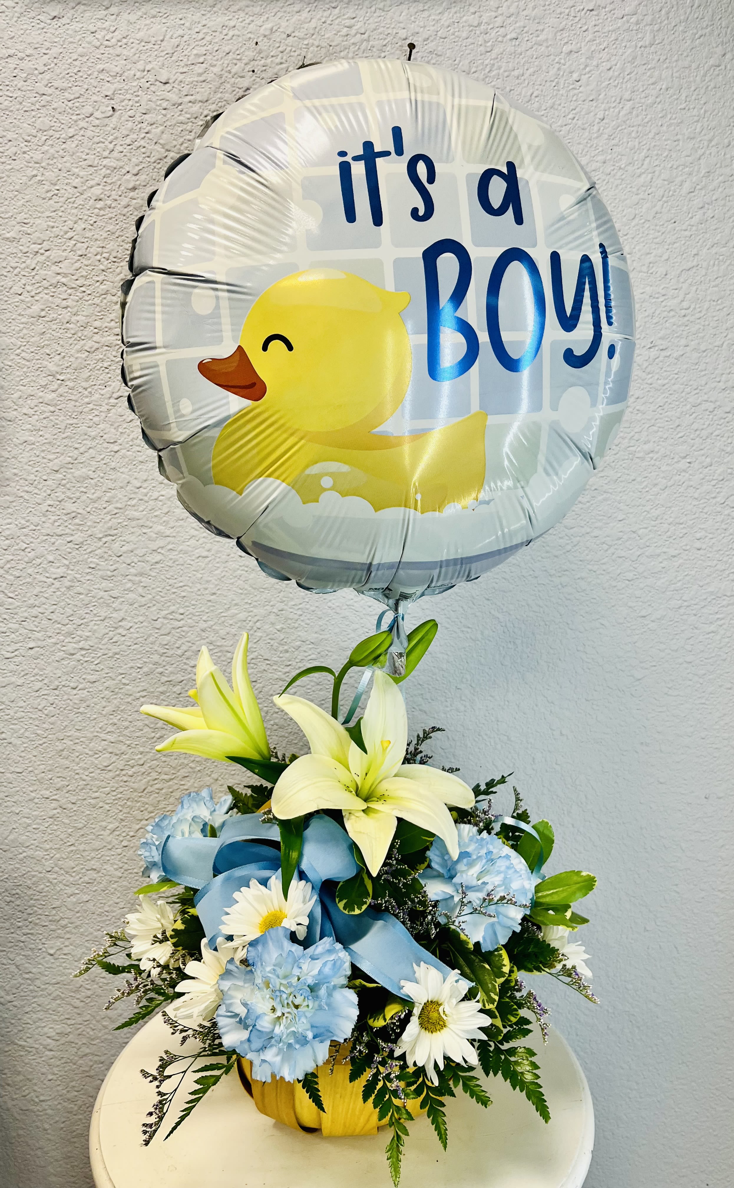 Duck-shaped balloon above a blue and white flower arrangement