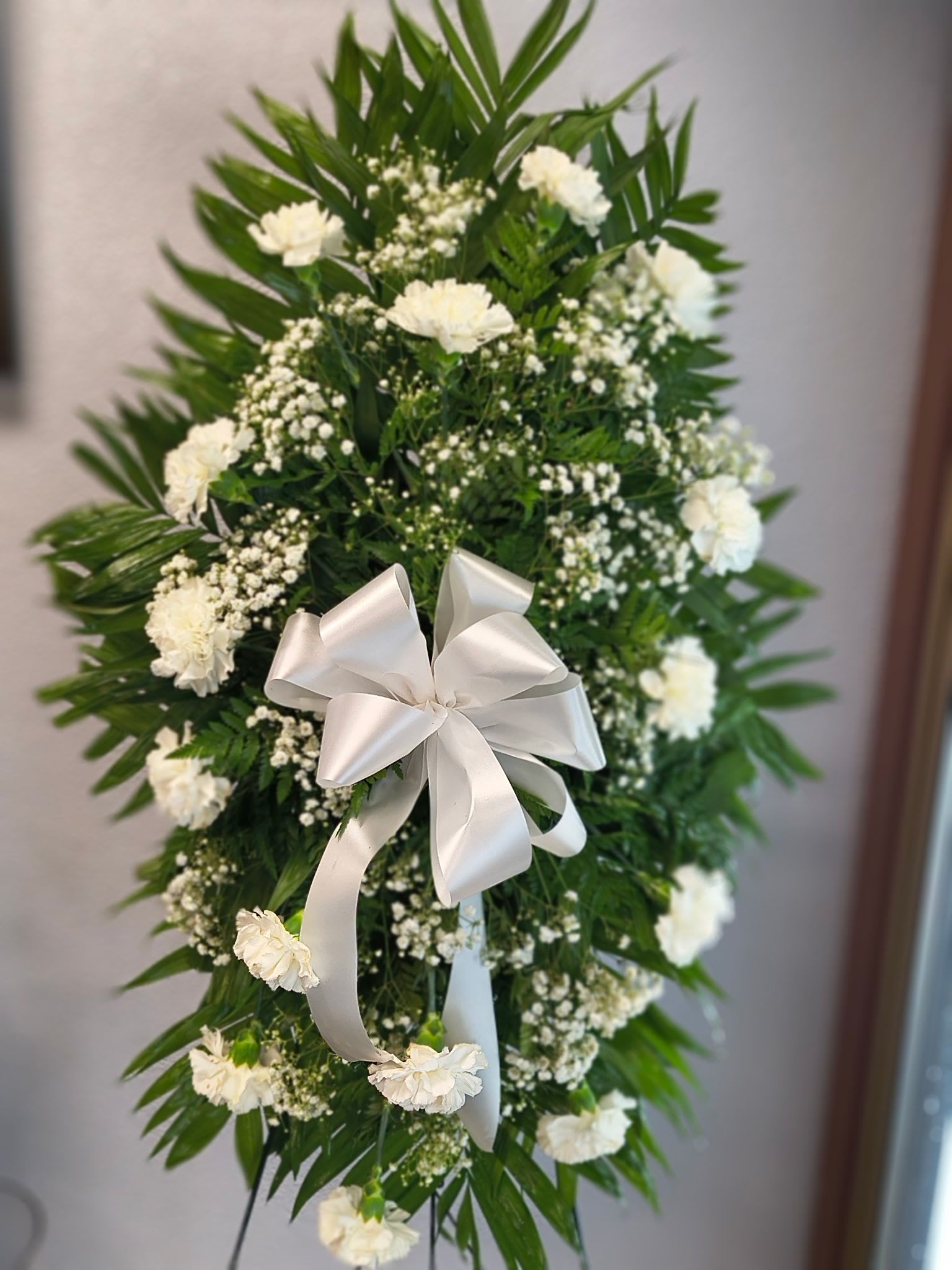 White floral standing spray with a satin bow