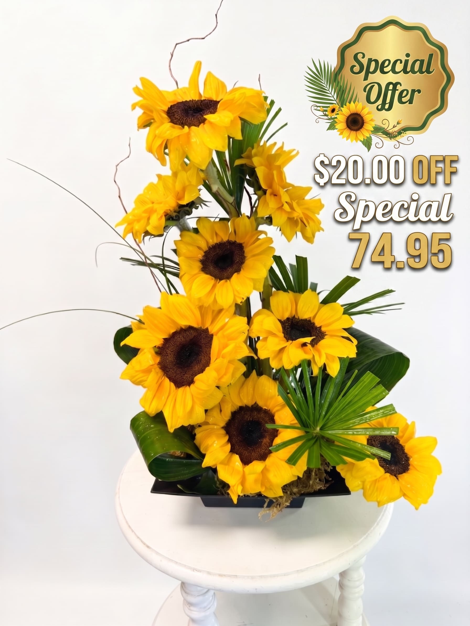 Midsommar Radiance - A dramatic, towering column of brilliant sunflowers rises in a bold, geometric tiered design, accented by crisp palm fans and structured greenery. Set in a sleek black container, the vivid yellow petals stand out in stark, graphic contrast, capturing a sense of perpetual summer and artistic tension. Equal parts mesmerizing and magnificent, it is the ultimate statement piece for those who appreciate floral design as an art form. Perfect for just about any occasion.