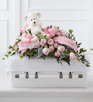 Pink rose arrangement with a teddy bear in a white casket