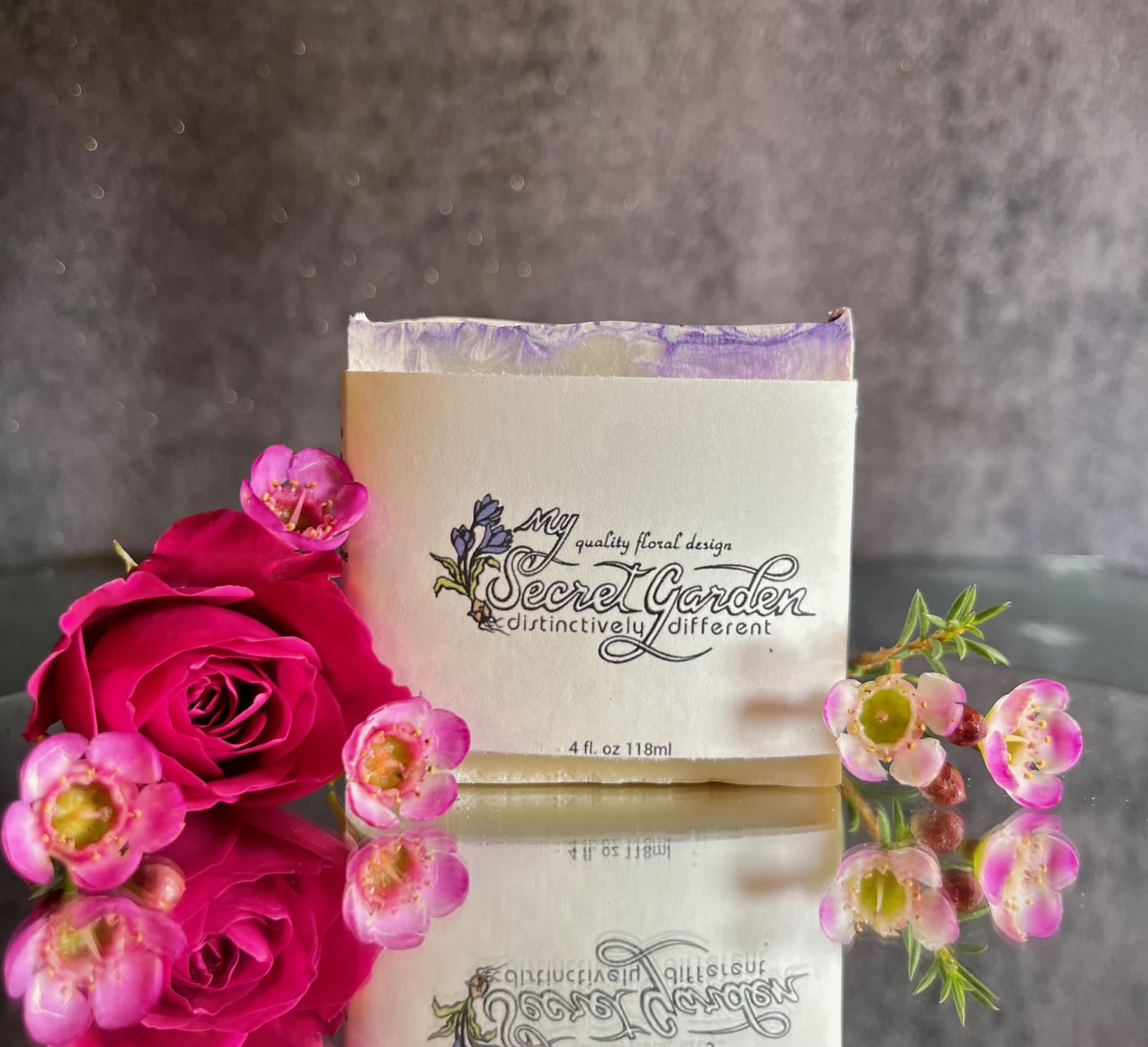 Pink roses and small pink blossoms arranged around a branded box