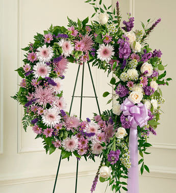 Large floral wreath on an easel with pink, purple, and white flowers