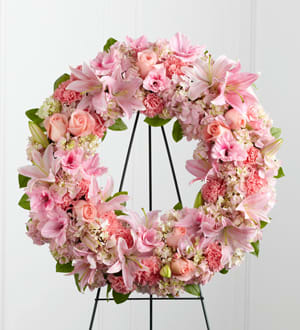 Pink floral wreath on a black metal stand