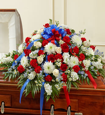 Large red, white, and blue floral spray on a casket with ribbons
