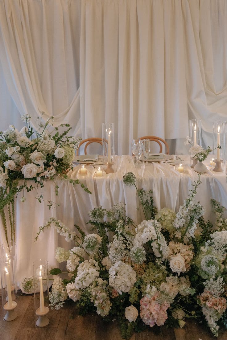 Ever After Sweetheart Table - A dreamy floral nest for the two of you. This design wraps your sweetheart table in soft blooms, airy textures, and gentle movement  like you’re sitting inside a garden scene. Perfect for photos, vows, and that just married glow. Colors are fully customizable to match your palette and vibe  from classic whites to blush, pastels, or something bold and modern. Romantic, intimate, and made to feel like your moment. Includes 1 top floral piece and 1 floor piece. Let me know your color scheme!