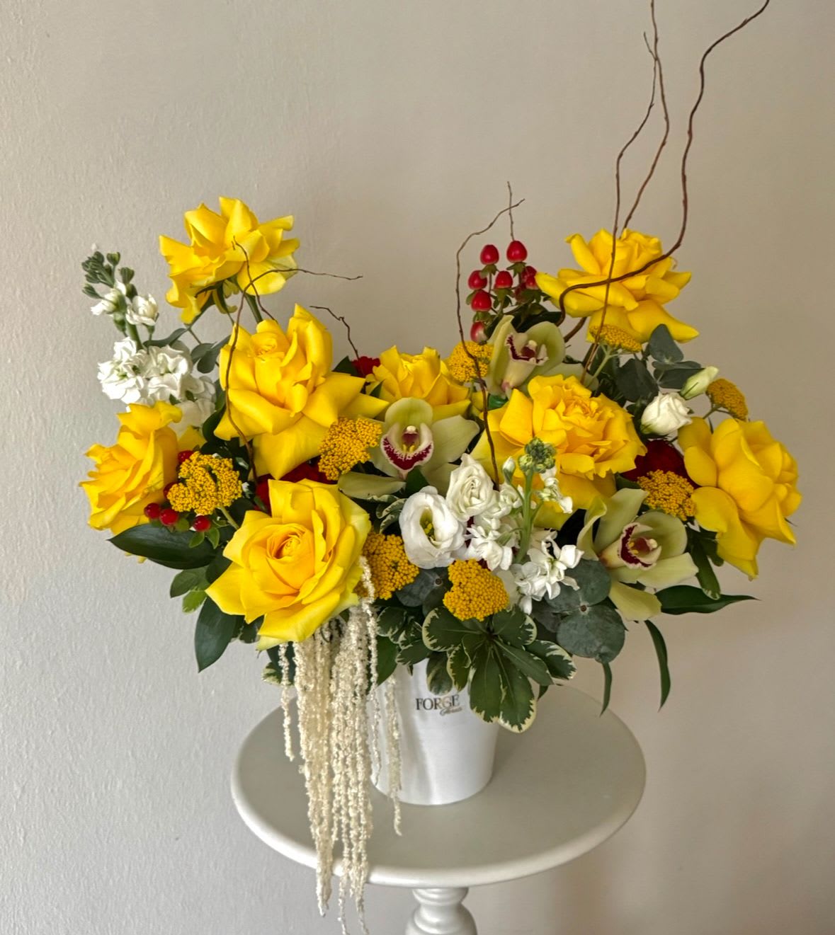 Sunshine Serenade - A bright and elegant arrangement featuring vibrant yellow roses, orchids, seasonal blooms, and textured accents in a modern ceramic container. Designed to bring warmth, joy, and a touch of luxury to any space.  Availability Note: Some flowers, including orchids and other seasonal blooms, may be substituted with flowers of equal or greater value based on seasonal availability while preserving the overall style and color palette.