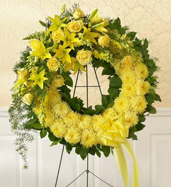 Yellow floral wreath on a black stand with a ribbon bow