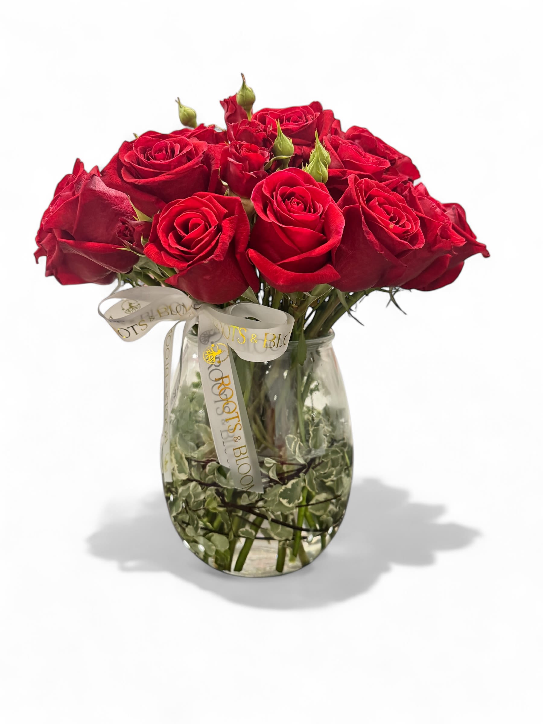 Red roses arranged in a clear glass vase with a ribbon bow
