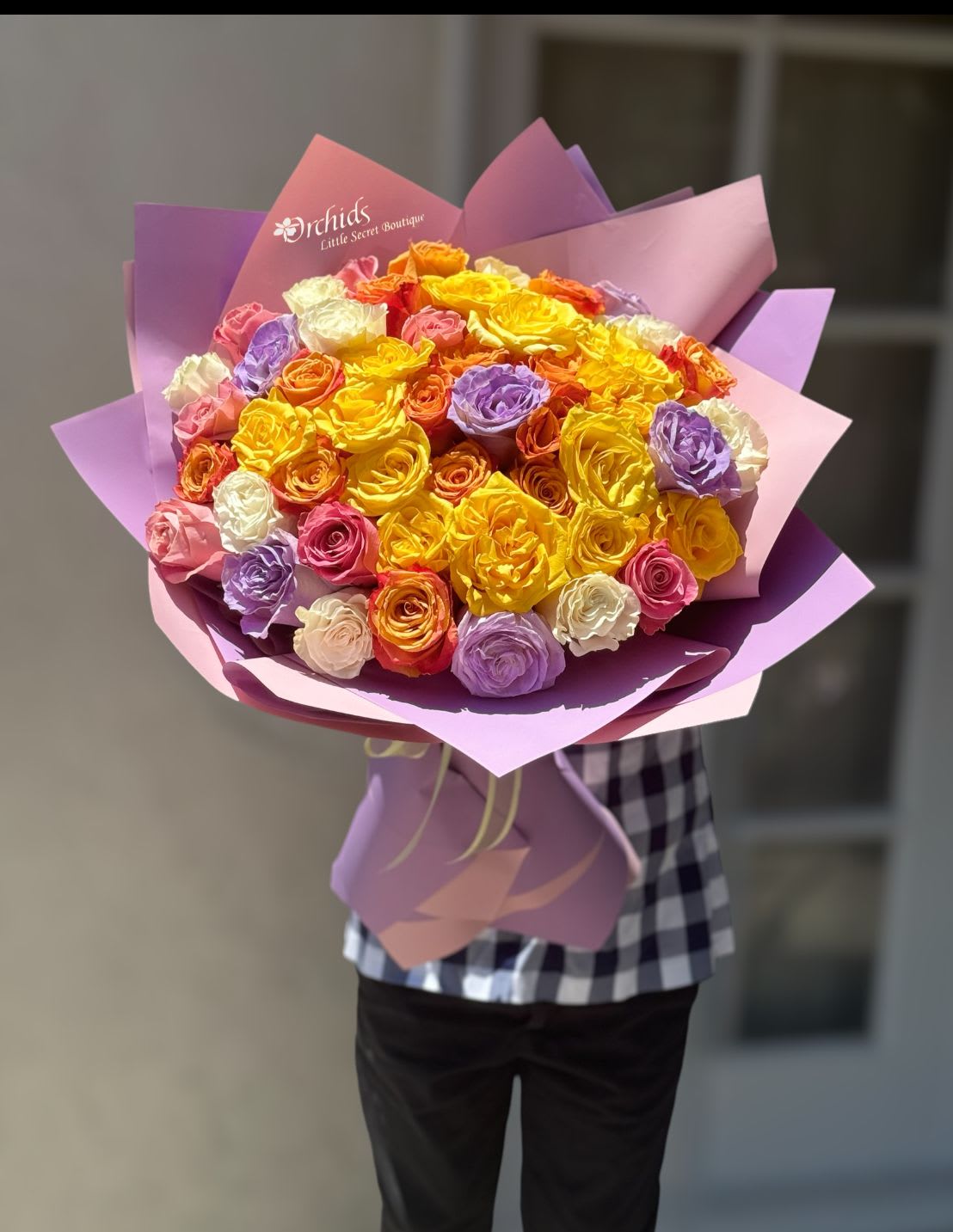 Large bouquet of multicolored roses wrapped in purple paper