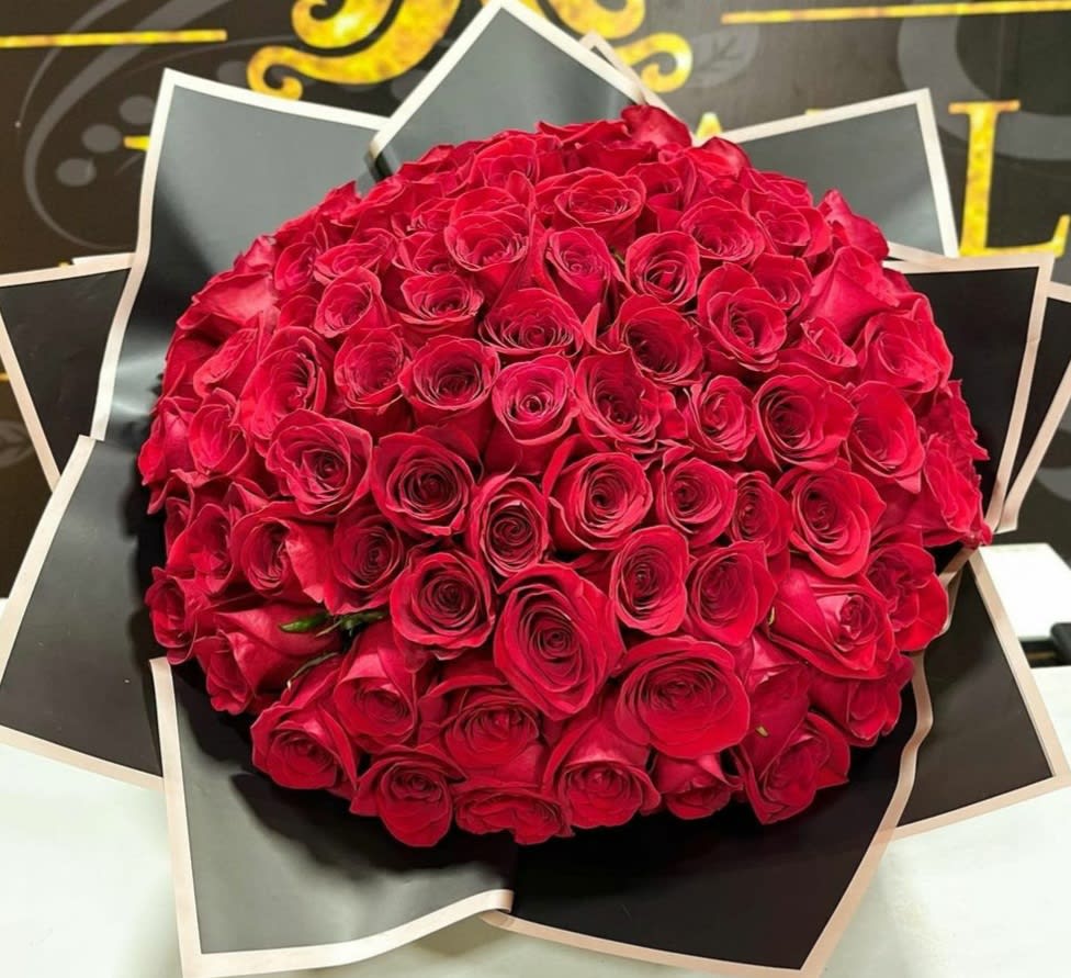 Round bouquet of red roses wrapped in black paper