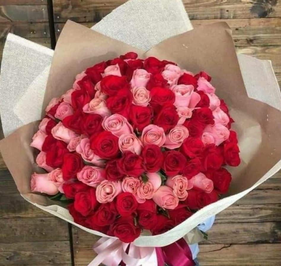 Large bouquet of red and pink roses wrapped in brown paper