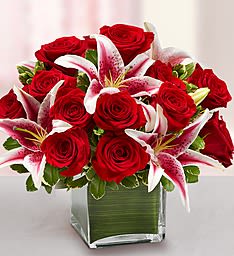 Red roses and pink lilies arranged in a square glass vase