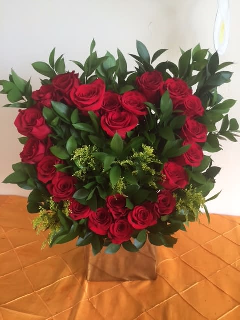 Heart-shaped bouquet of red roses with greenery in a box