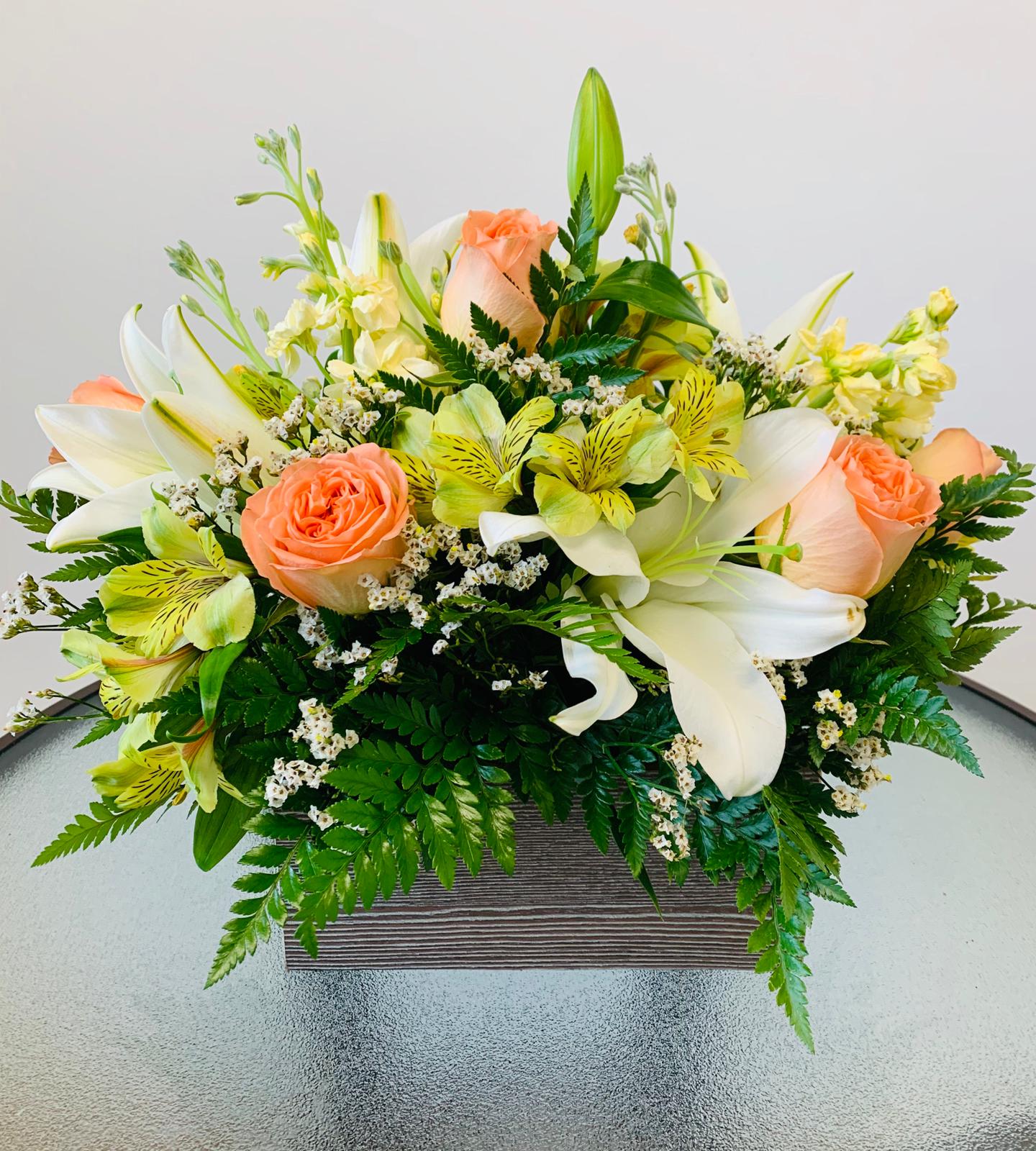 Peach roses and white lilies in a low rectangular container
