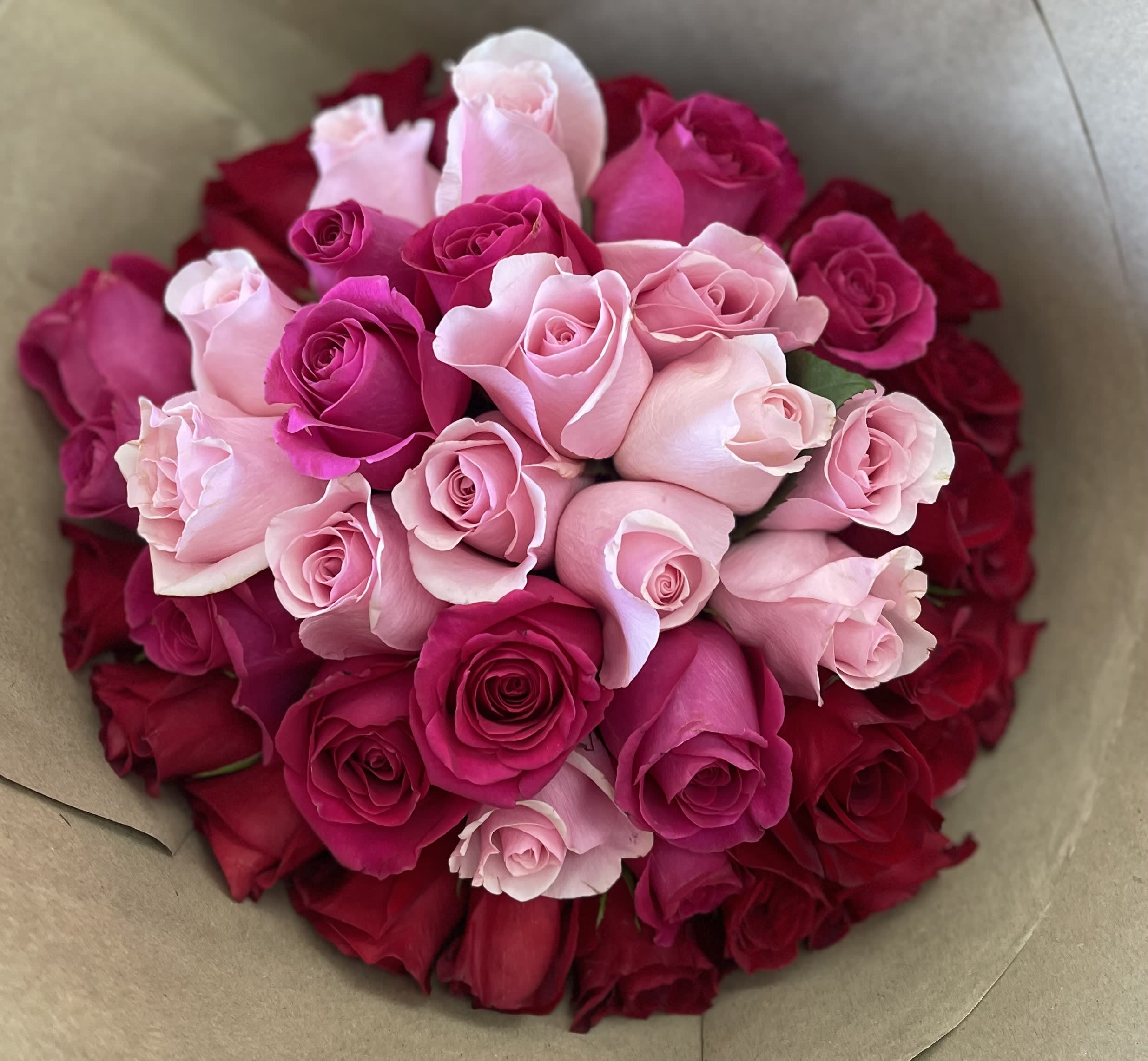 Bouquet of pink and red roses wrapped in brown paper