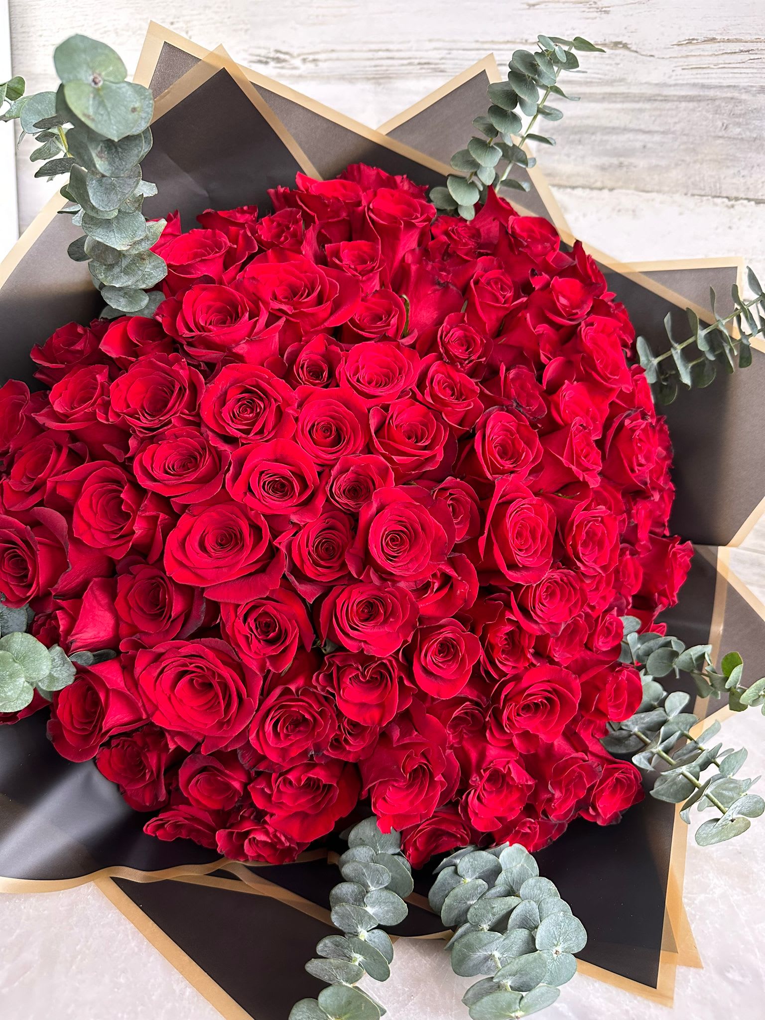 Hold the Rose - 100 long stem red roses in a hand crafted Bouquet