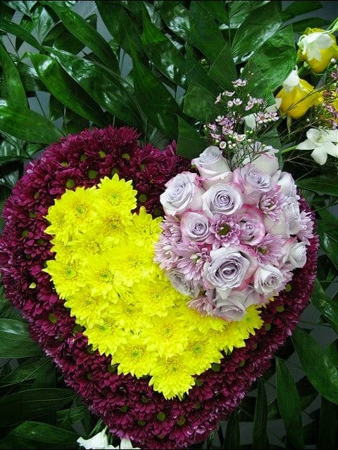 Heart-shaped floral arrangement with yellow, purple, and pale pink flowers