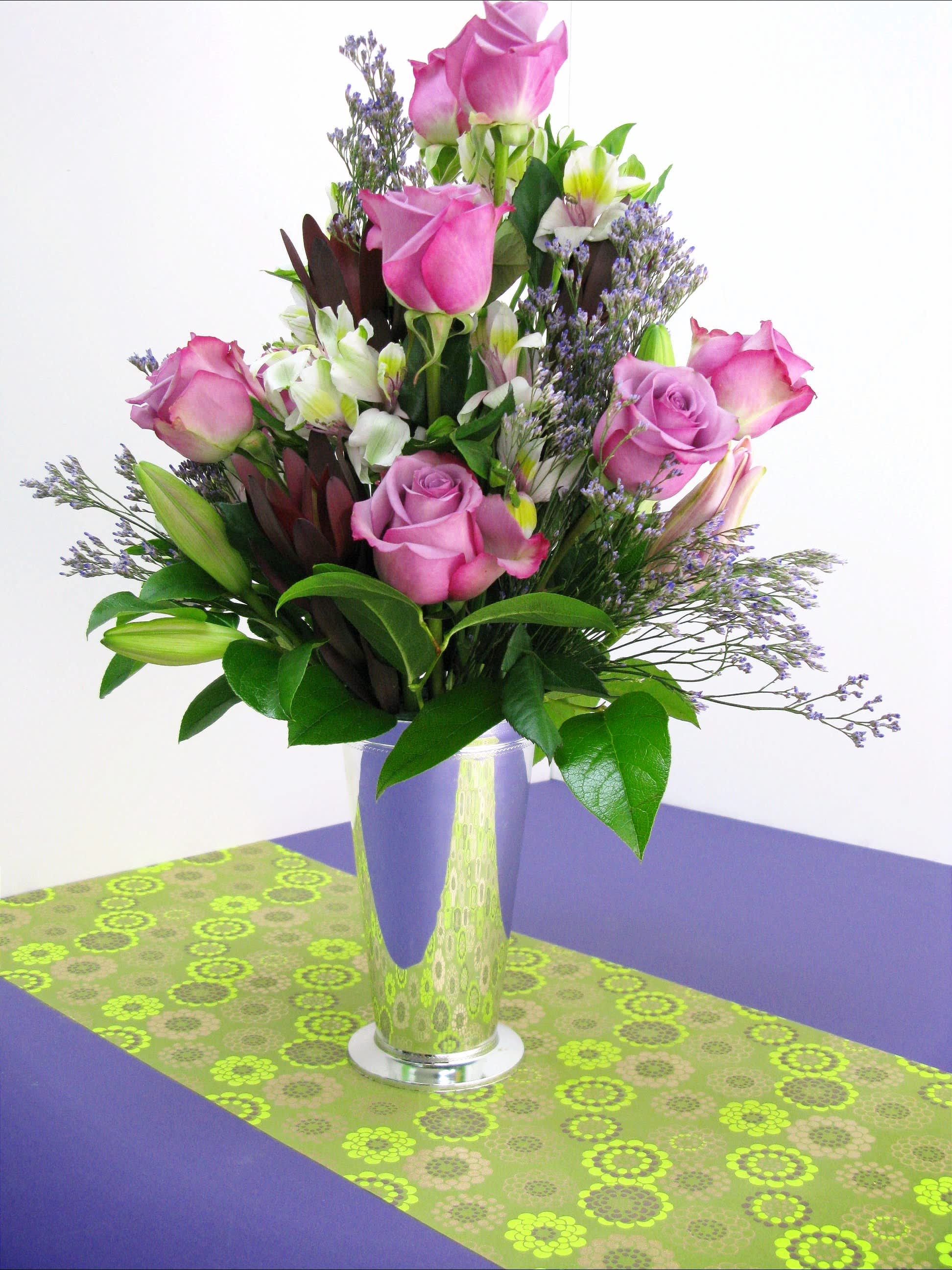 Pink roses and lilies arranged in a tall glass vase