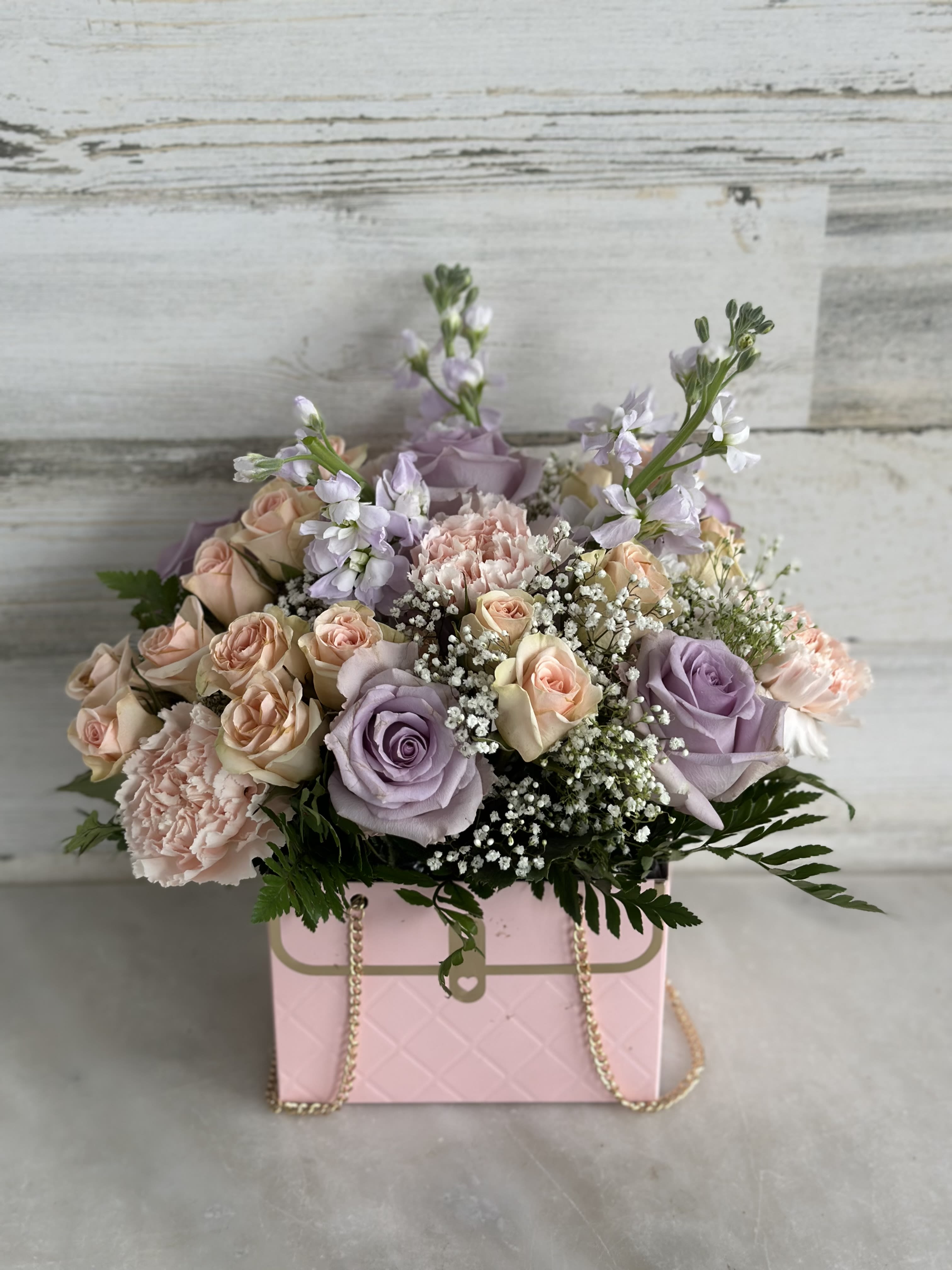 Pastel rose bouquet in a pink box with gold chain handles