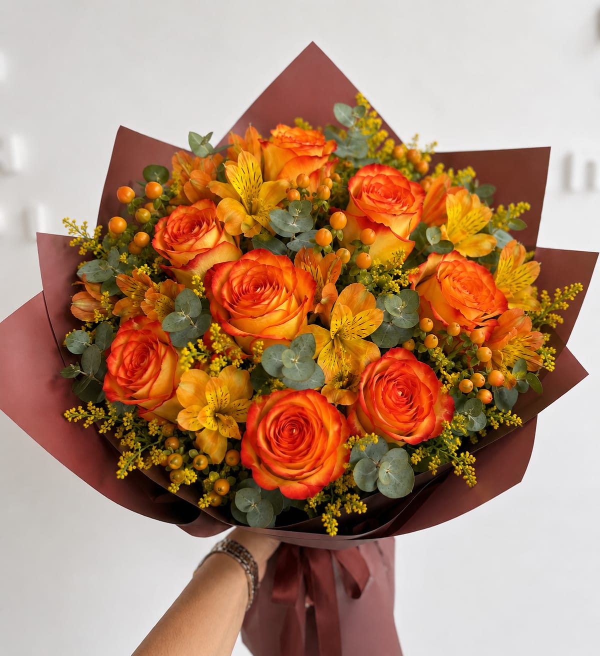 Bouquet of orange roses and yellow alstroemeria with burgundy wrap