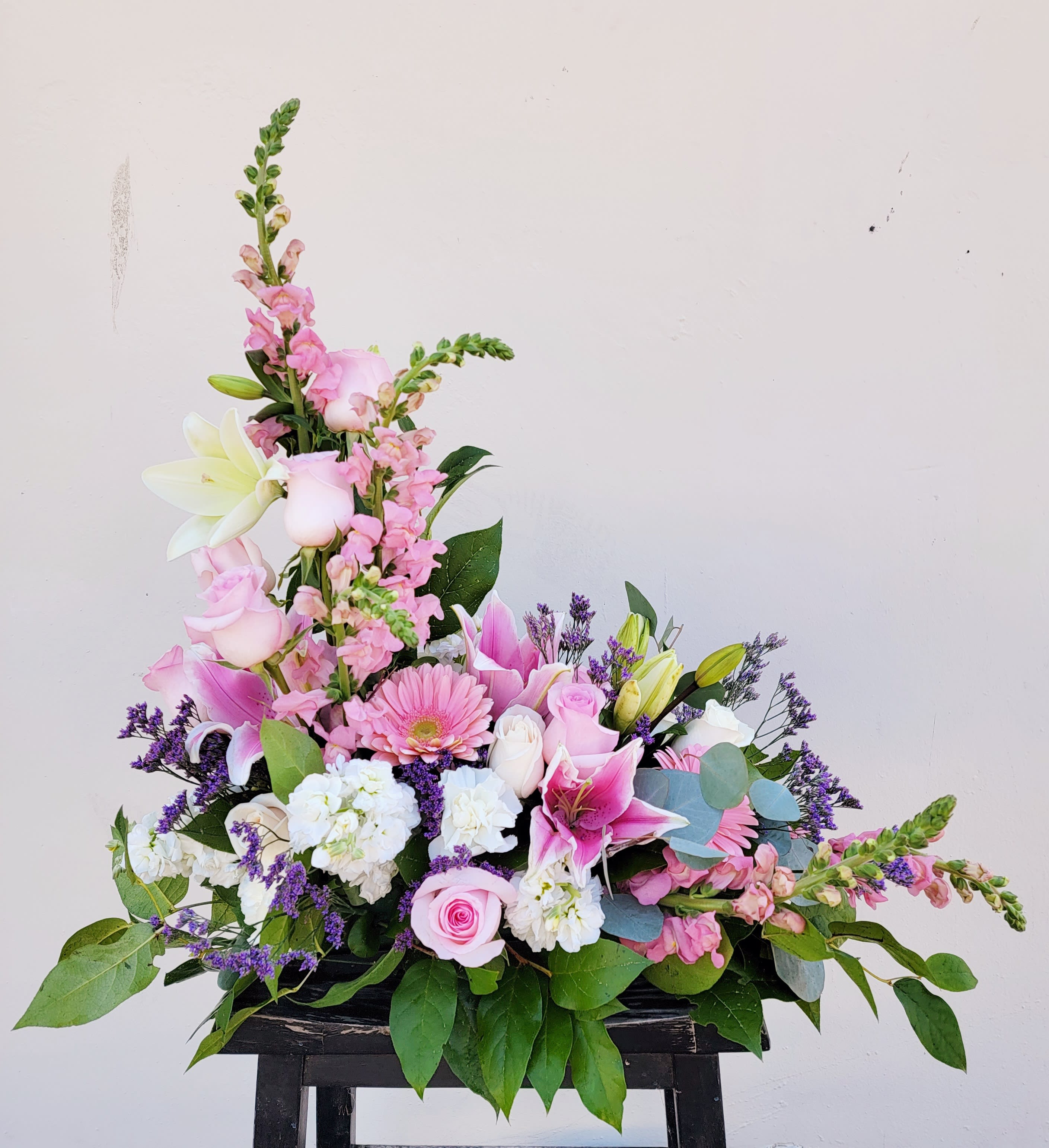 Pink and white floral arrangement with lilies and roses in a low container