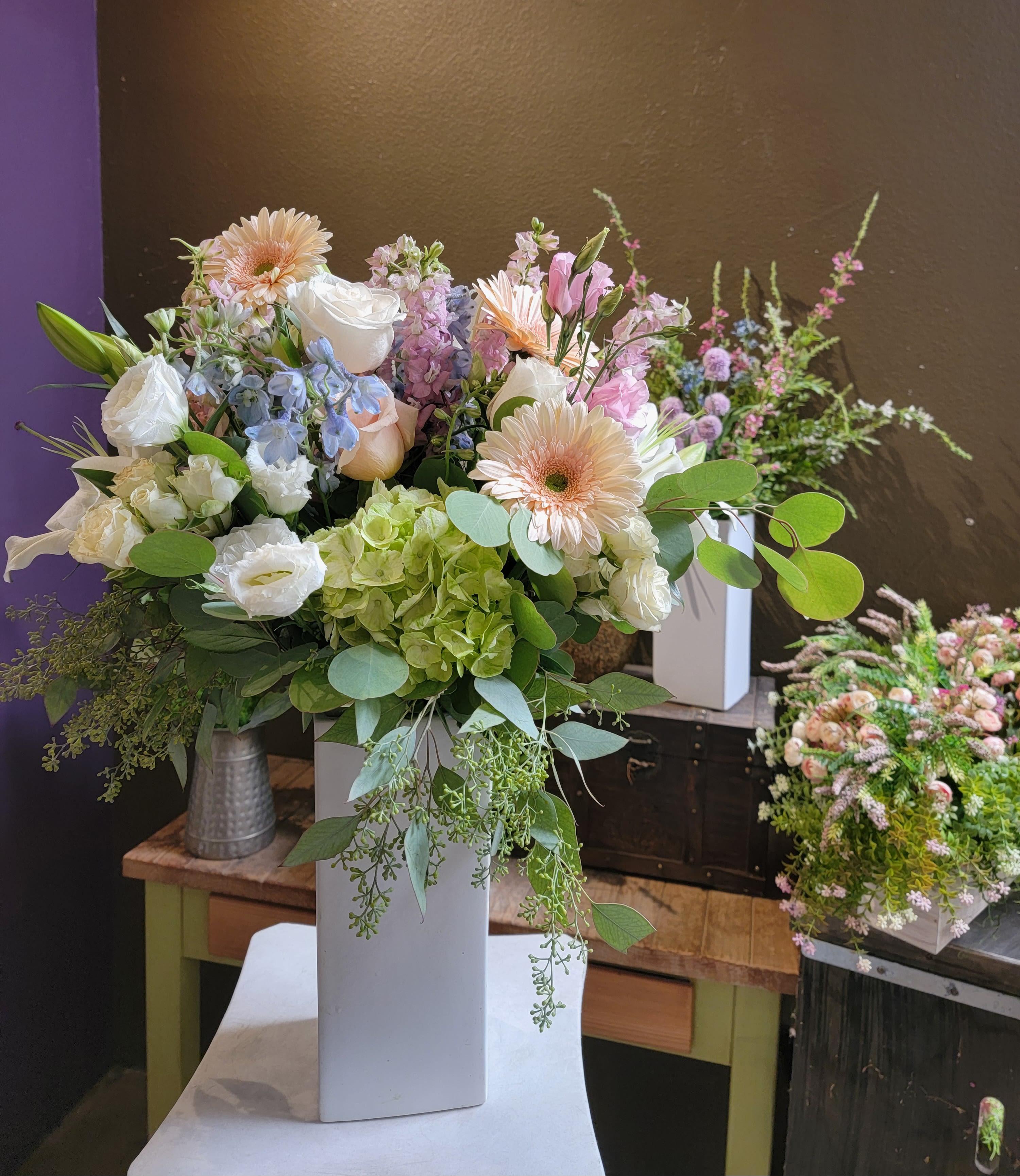 Mixed pastel bouquet in a tall white vase with gerberas, roses, and hydrangeas